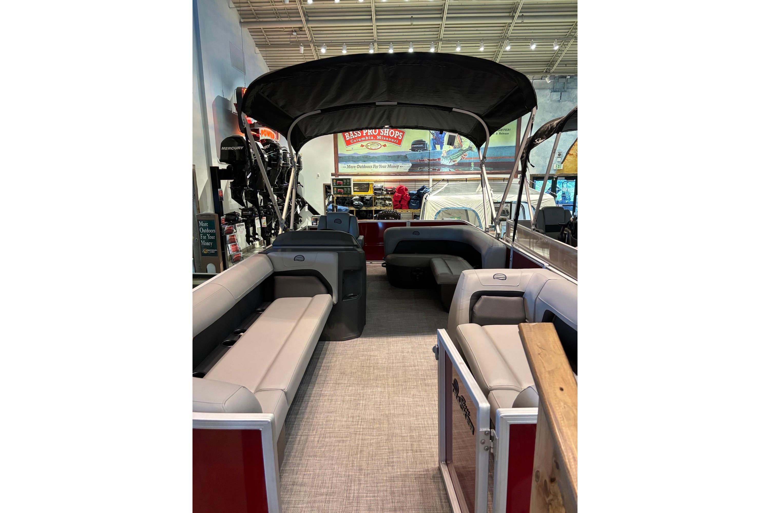 2026 Sun Tracker Party Barge 18 DLX interior with seating and canopy in showroom.
