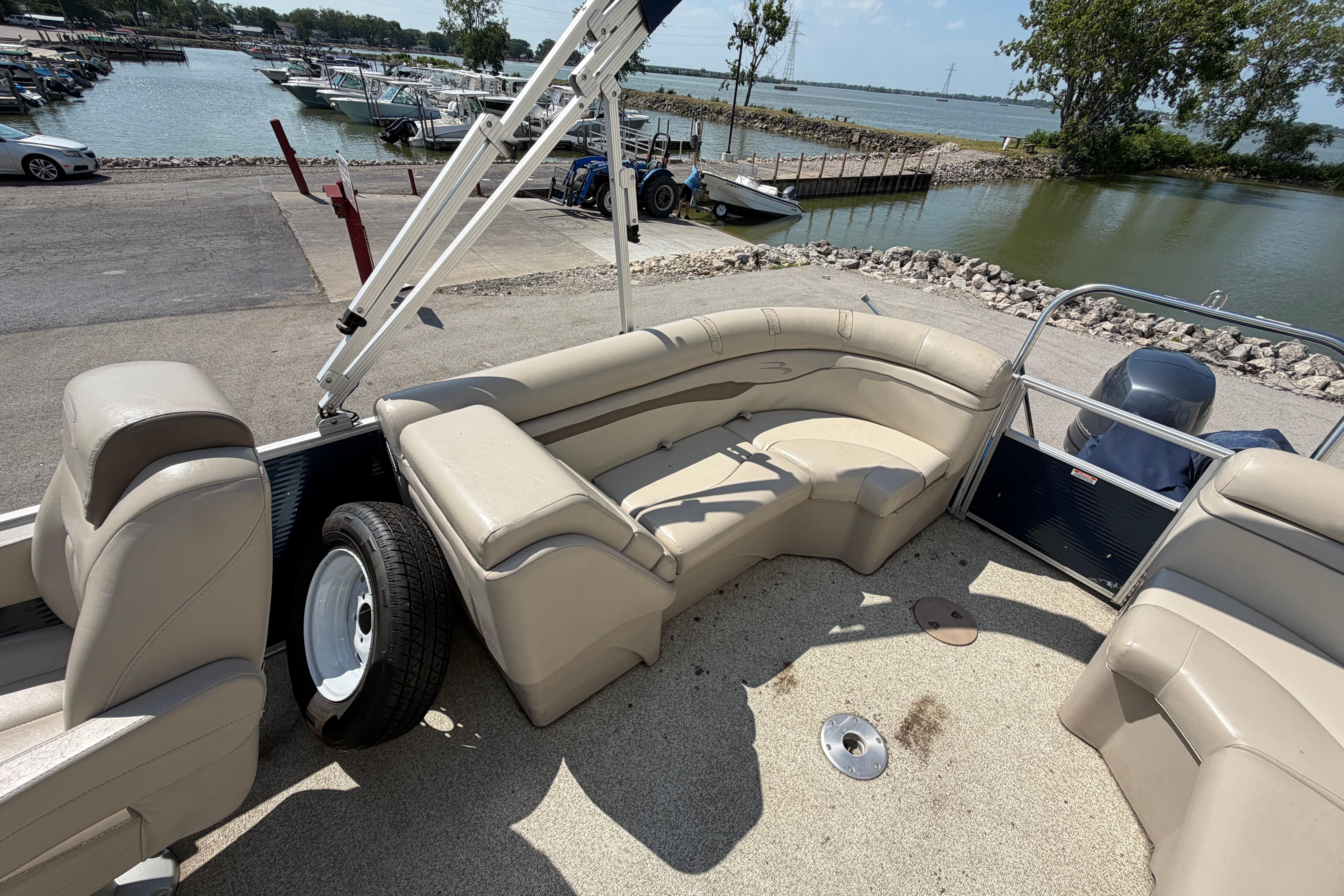 2017 Bennington 25 SSXAPG pontoon boat with beige seating, docked by a scenic lake.