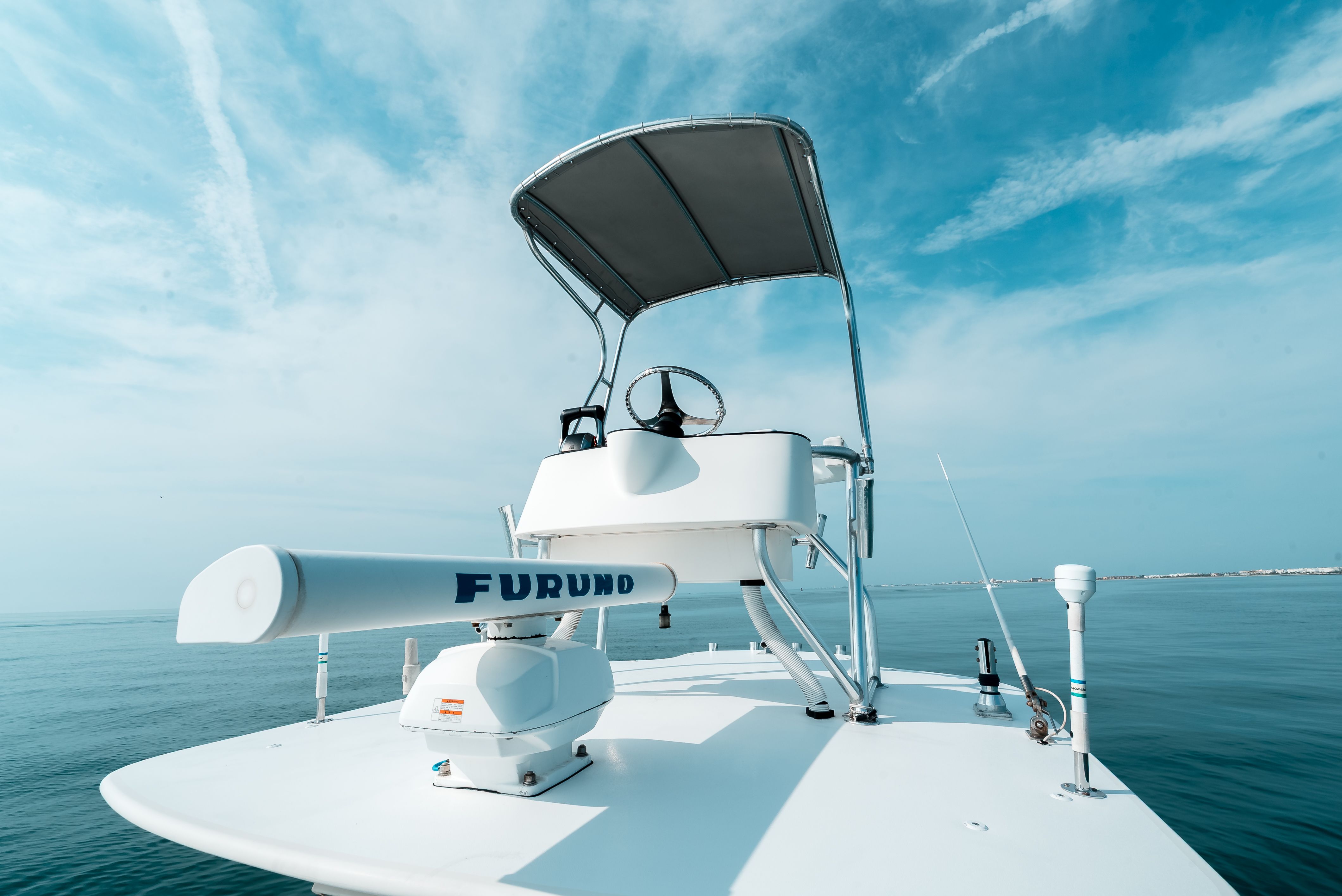 A boat with an elevated helm and sunshade on calm water.