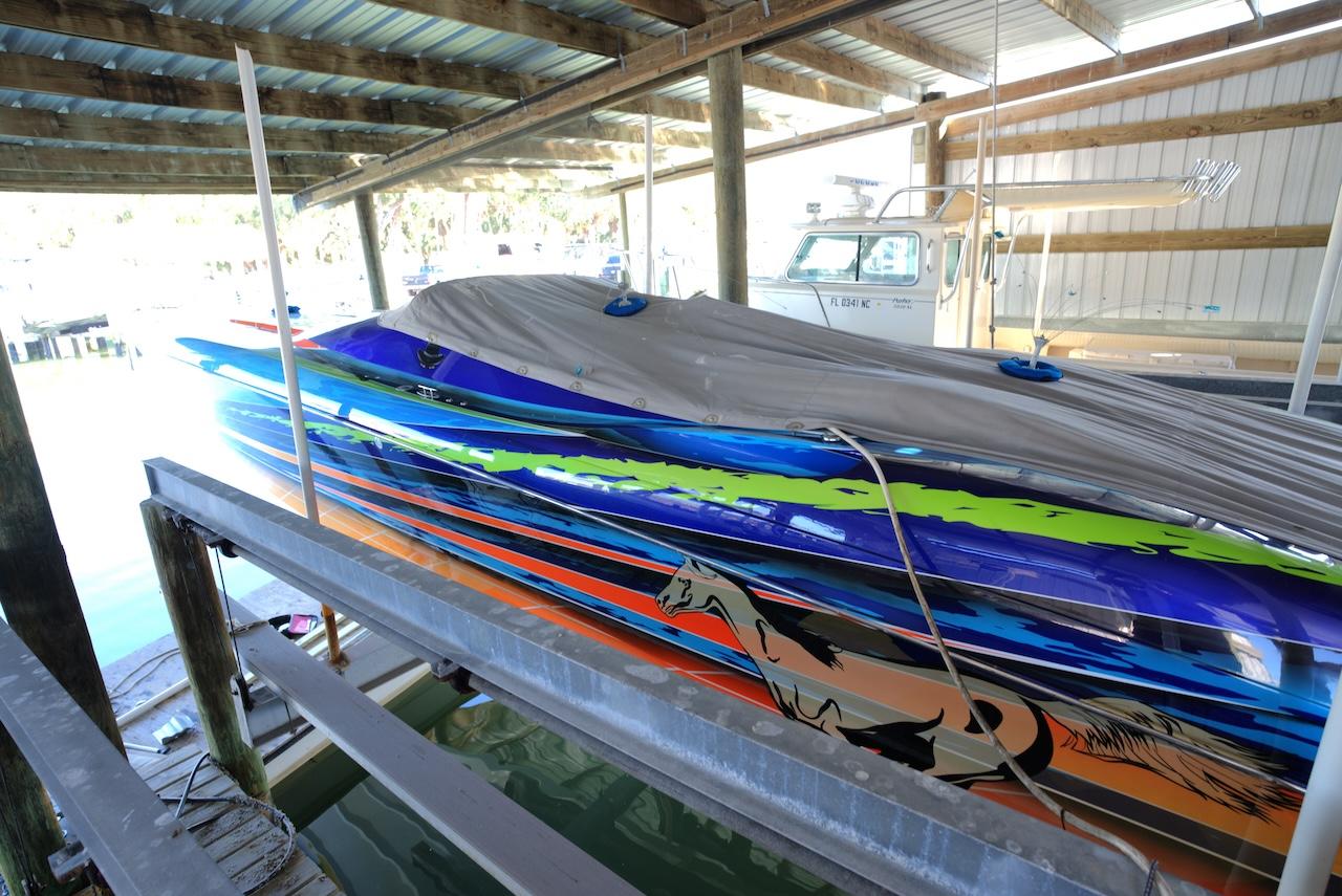 2008 Outerlimits 39 Quattro speedboat with vibrant graphics, docked under a covered structure.