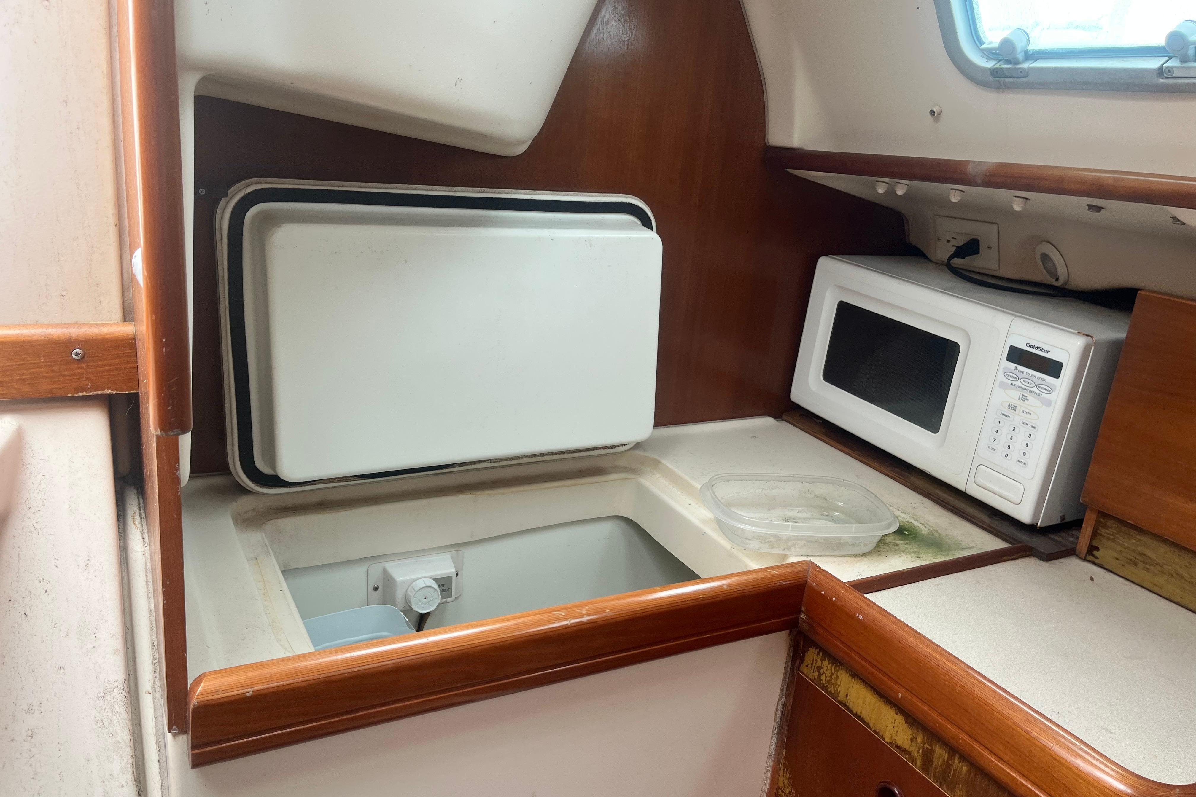 Interior of 1999 Benneteau 321 Oceanis yacht kitchen with microwave and storage.