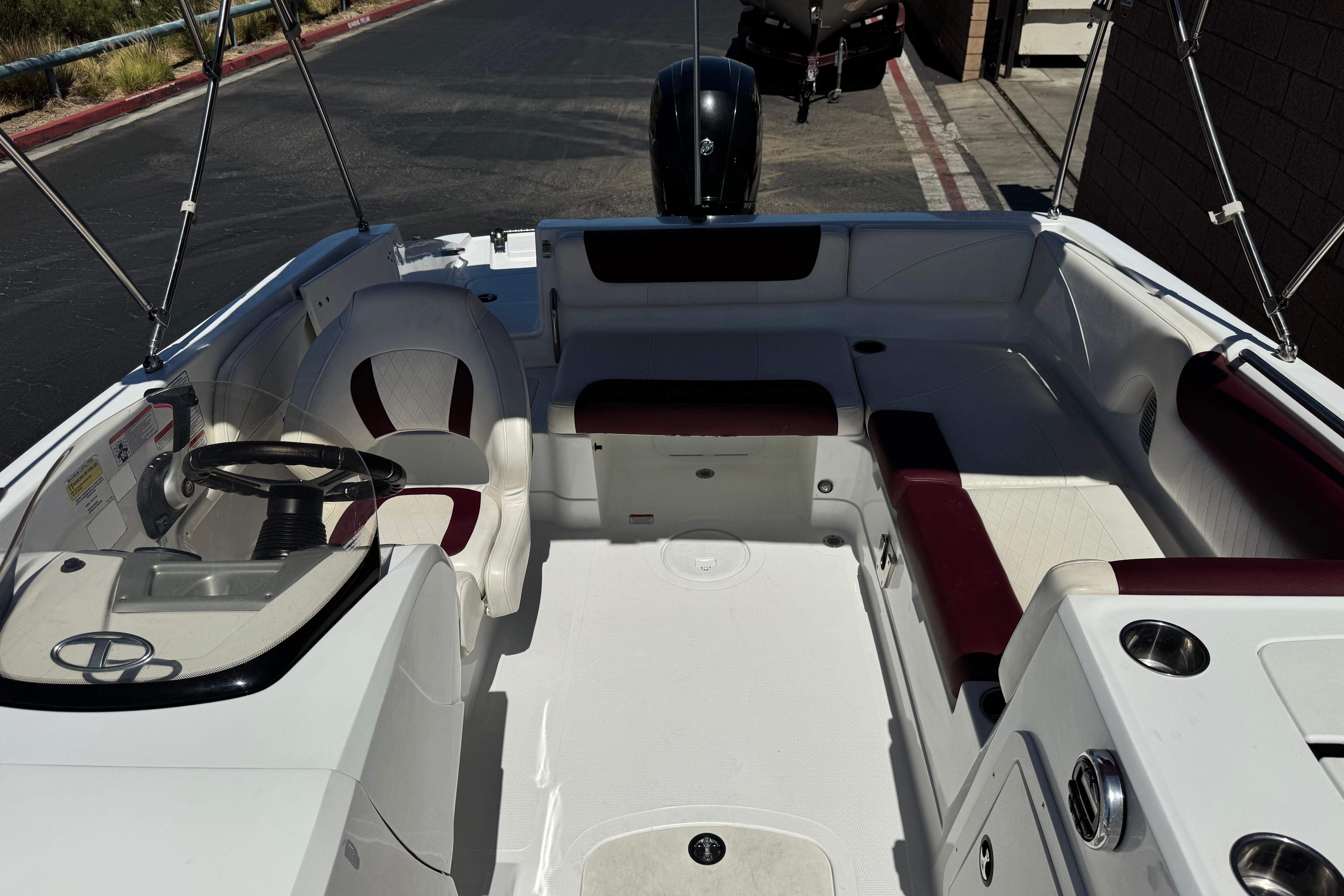 2017 Tahoe 2150 boat interior with seating and steering wheel, parked on pavement.
