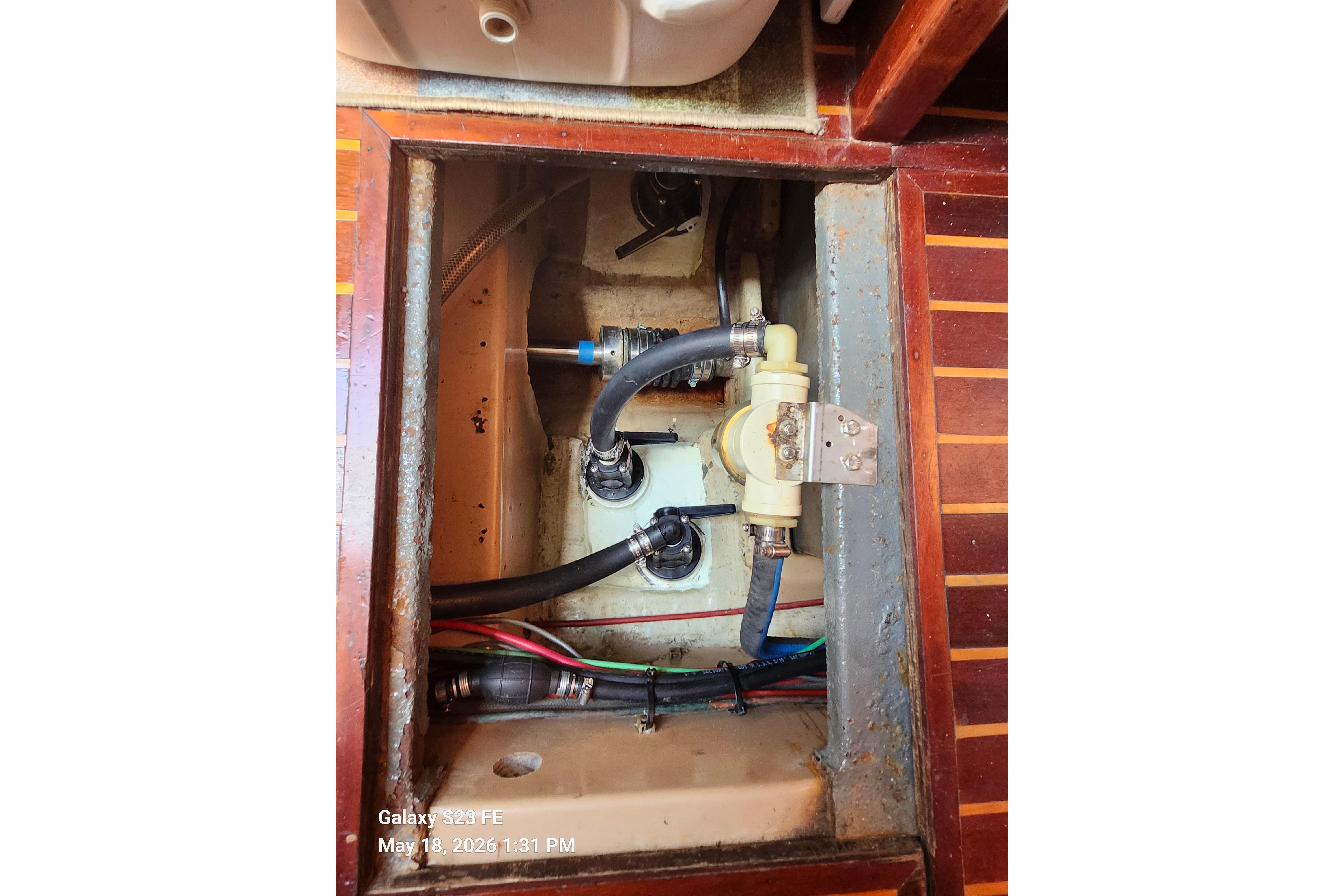 Bilge area of a 1986 Beneteau Idylle 15.50 sailboat, showing hoses and fittings.