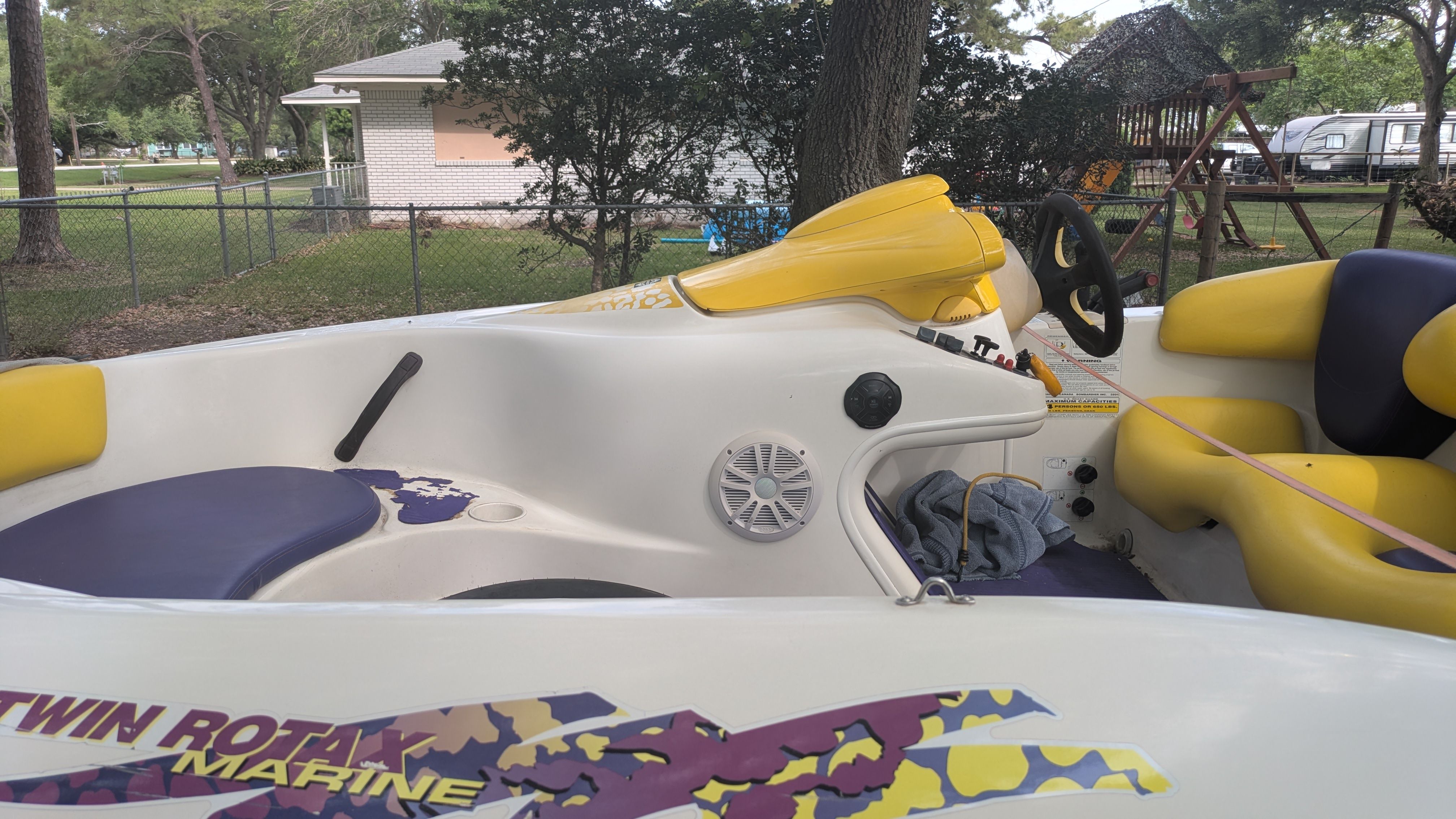 A 1995 Bombardier SeaDoo SPEEDSTER with yellow and purple seats, parked in a yard.