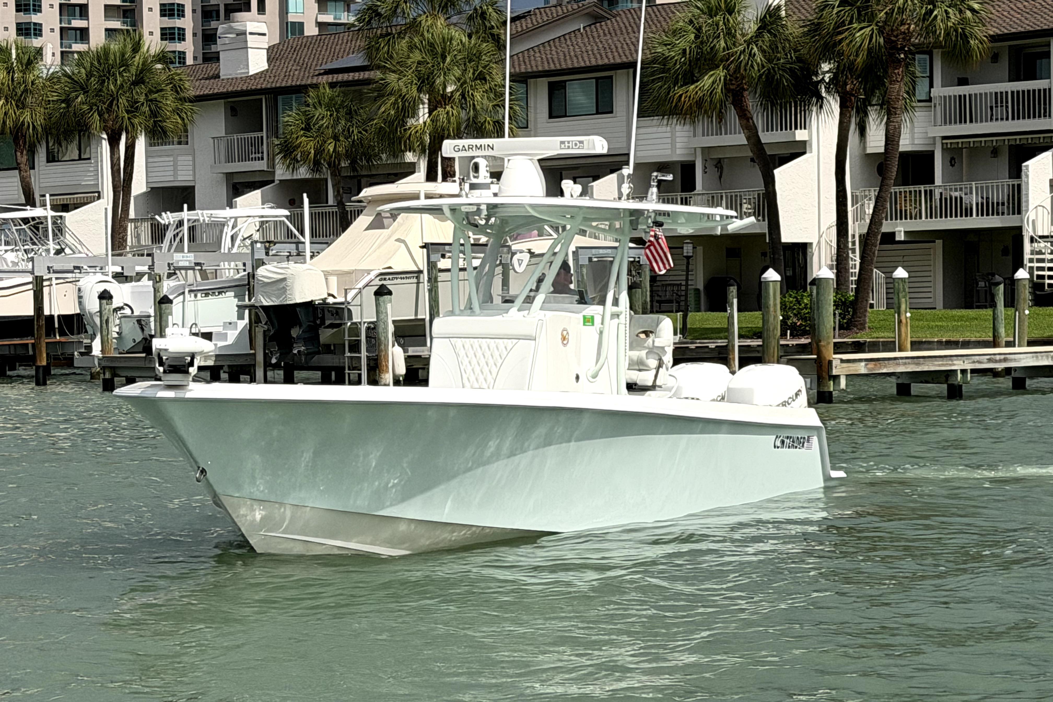 2019 Contender 30 ST boat docked near waterfront homes with palm trees.