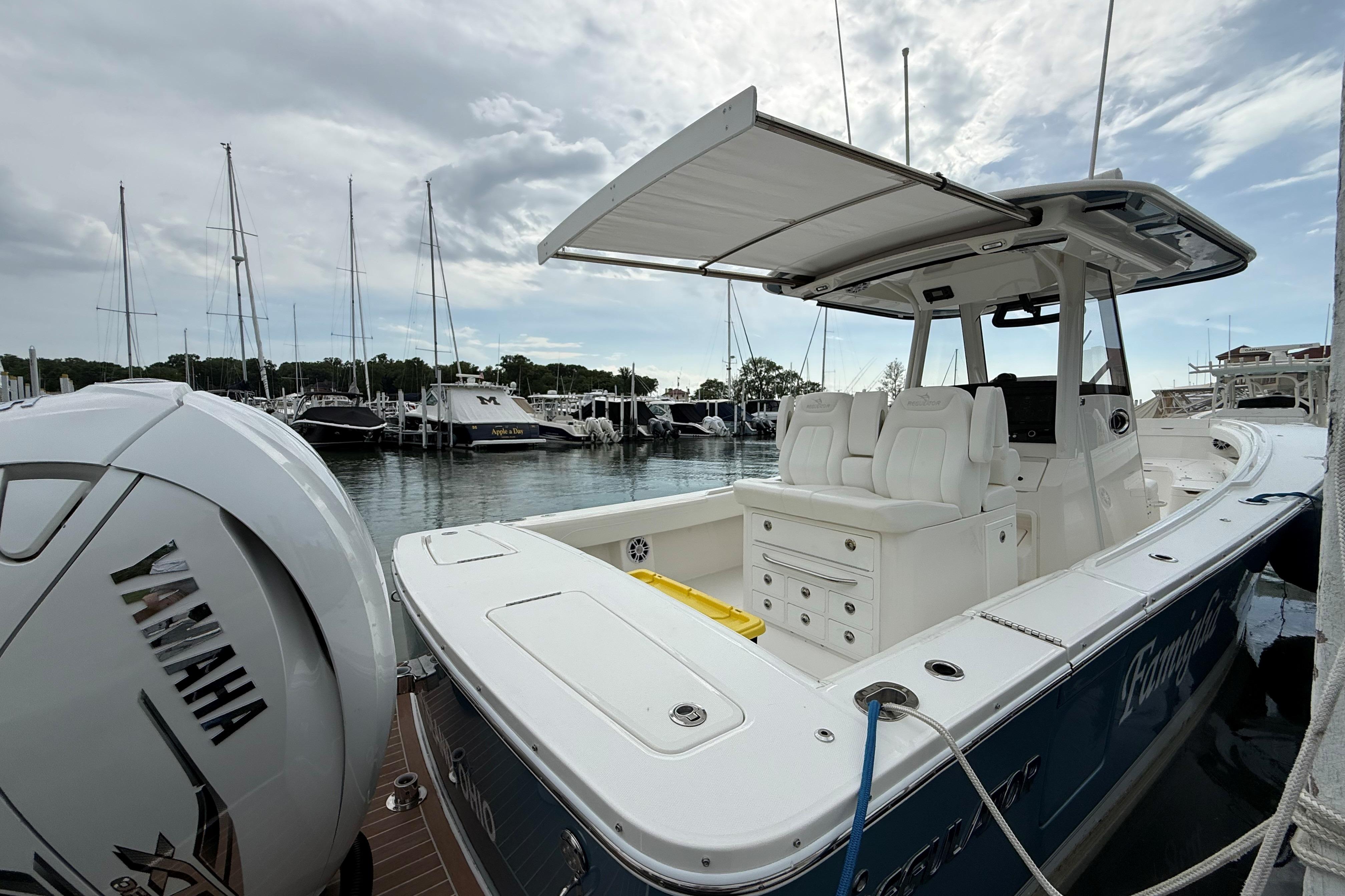 2021 Regulator 31 boat docked, featuring Yamaha engine, with marina and sailboats in background.