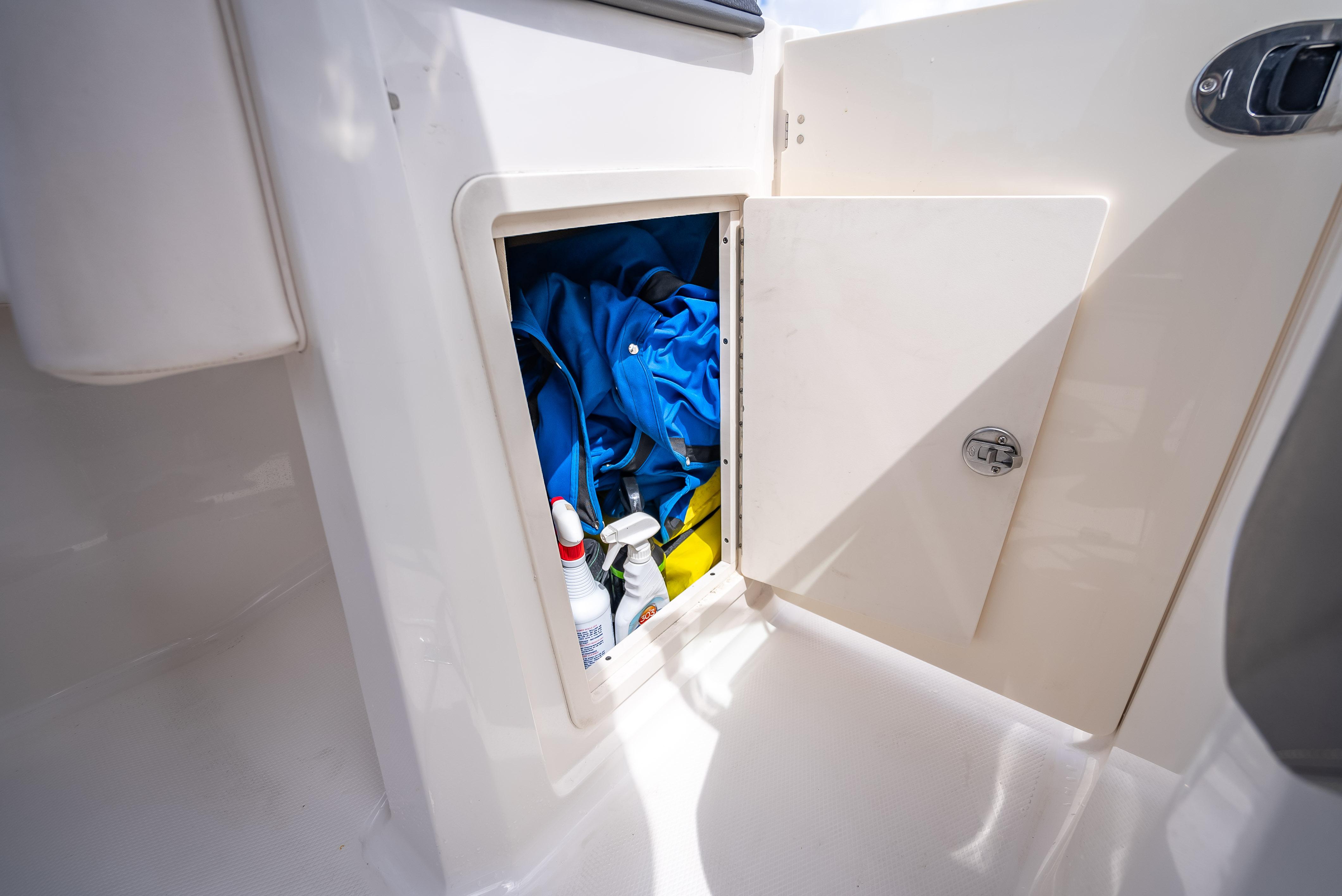 Storage compartment on 2017 Chaparral 227 SSX boat with cleaning supplies and blue fabric.