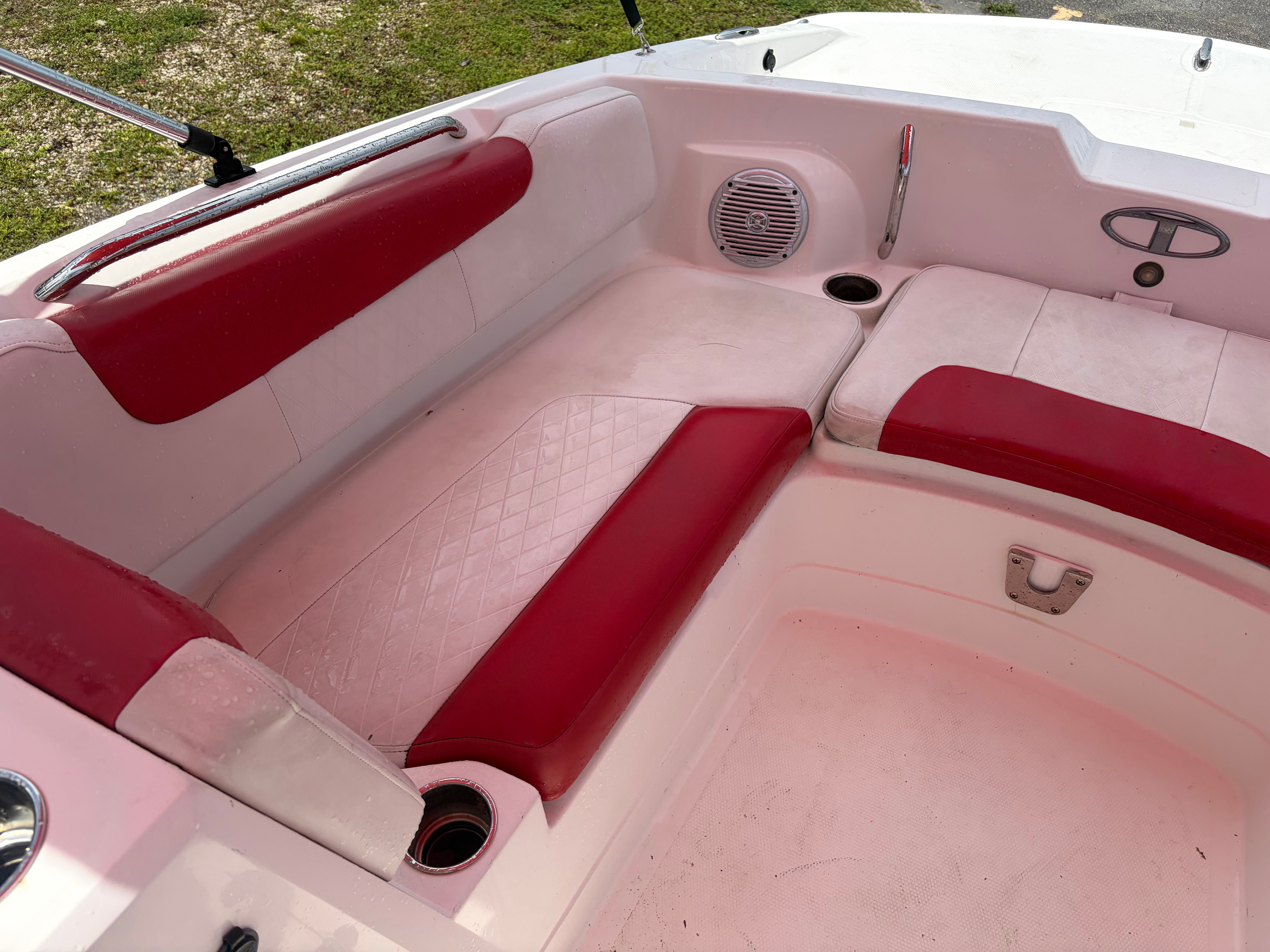 Red and white seating area in a boat with speaker and cup holders.