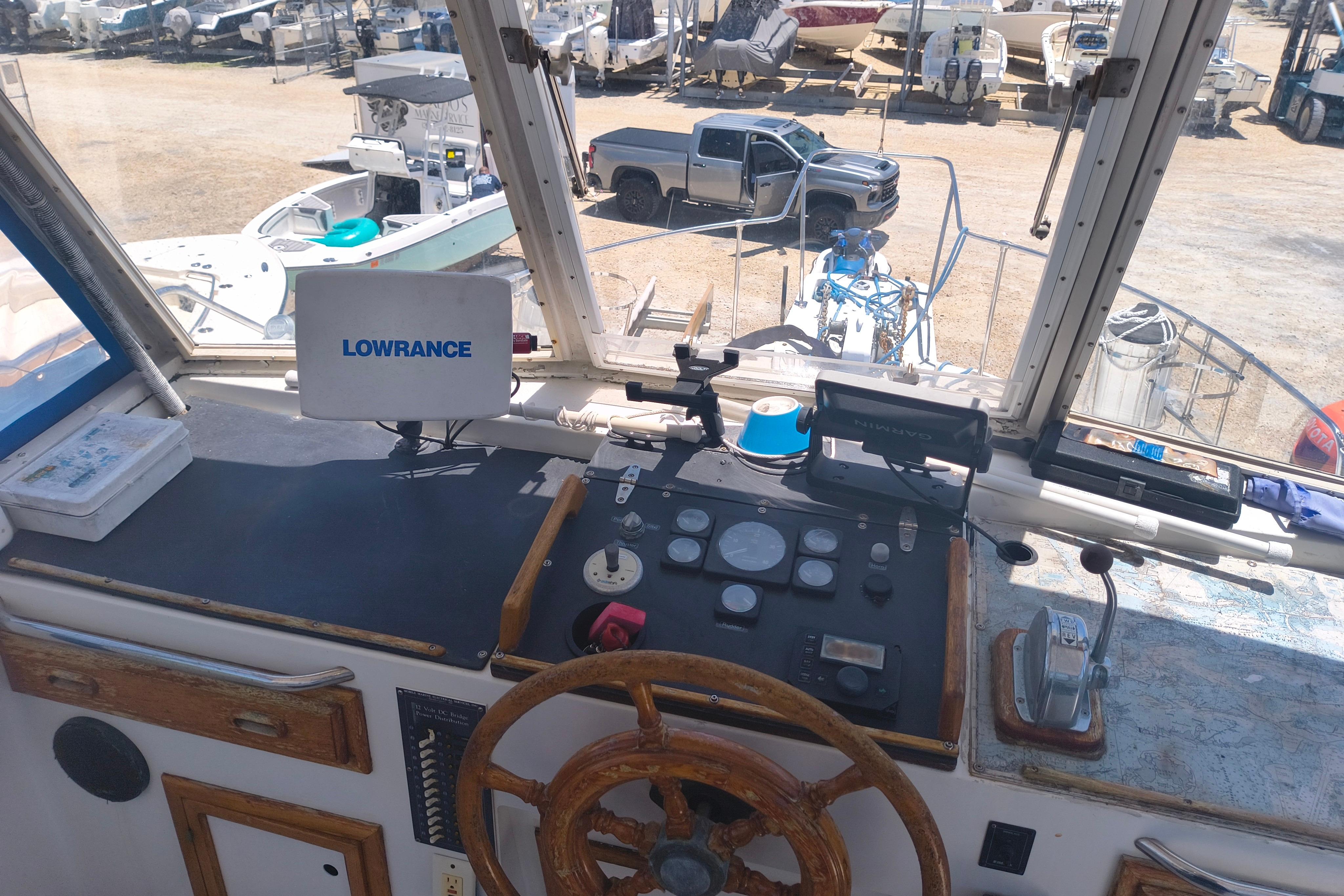 1984 Kadey-Krogen Manatee helm with navigation equipment and steering wheel in a boatyard setting.