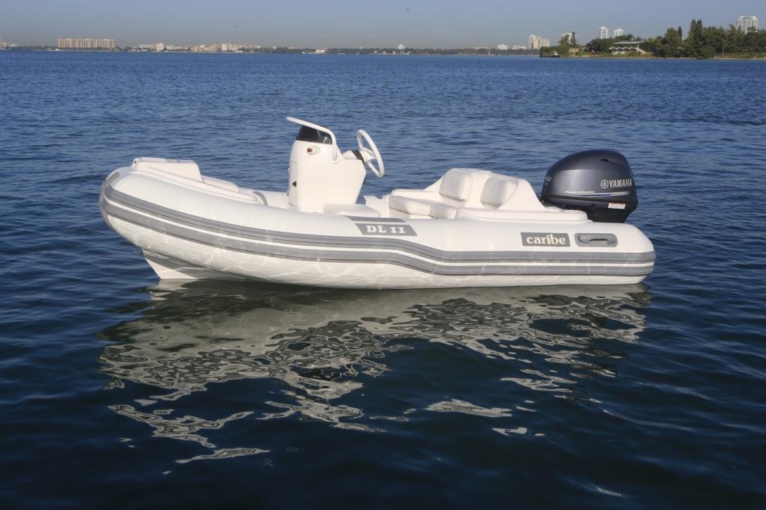 2025 Caribe DL11 inflatable boat on calm water with Yamaha outboard motor.