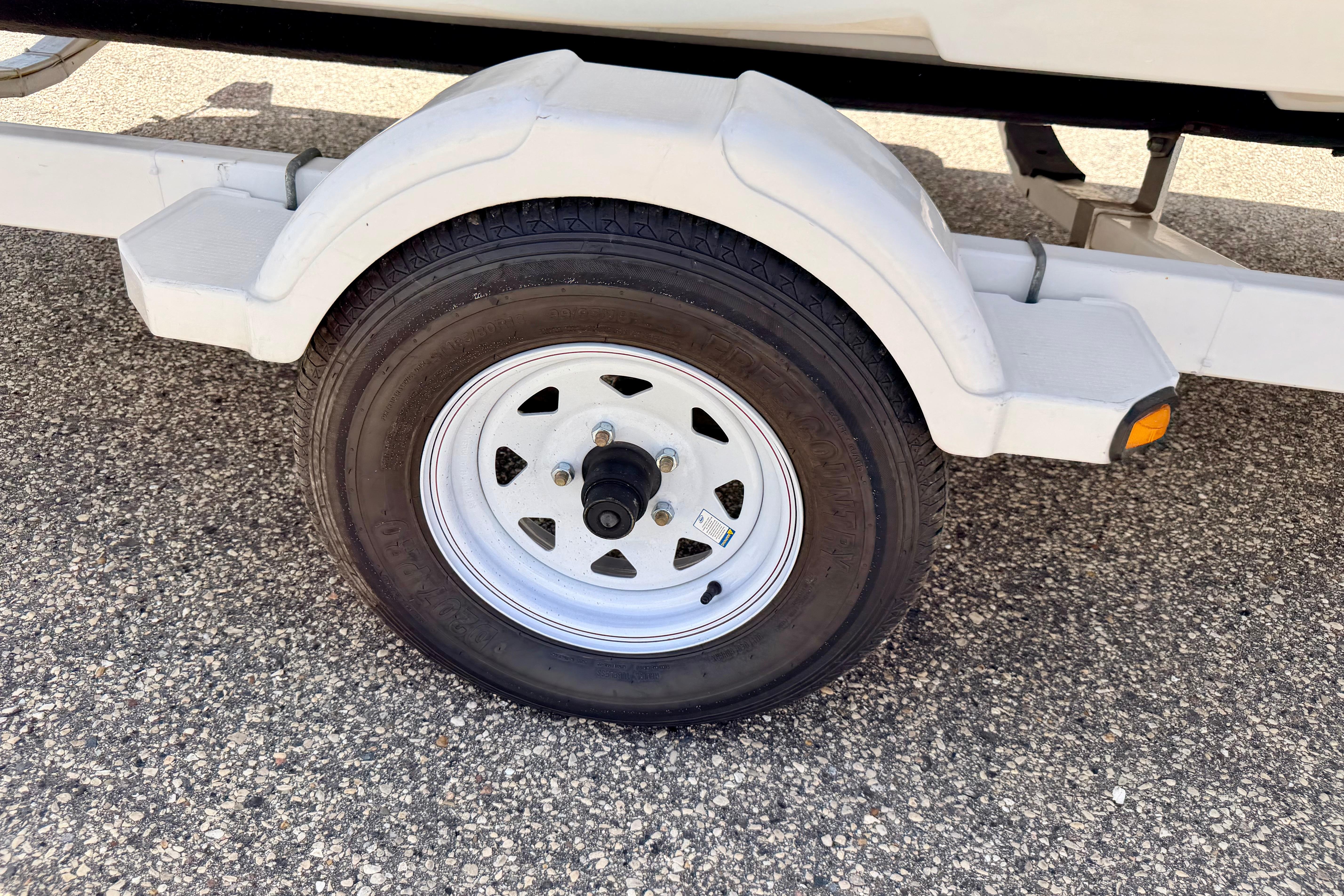 Trailer wheel of a 2004 Bombardier SEADOO Utopia 185 on asphalt surface.