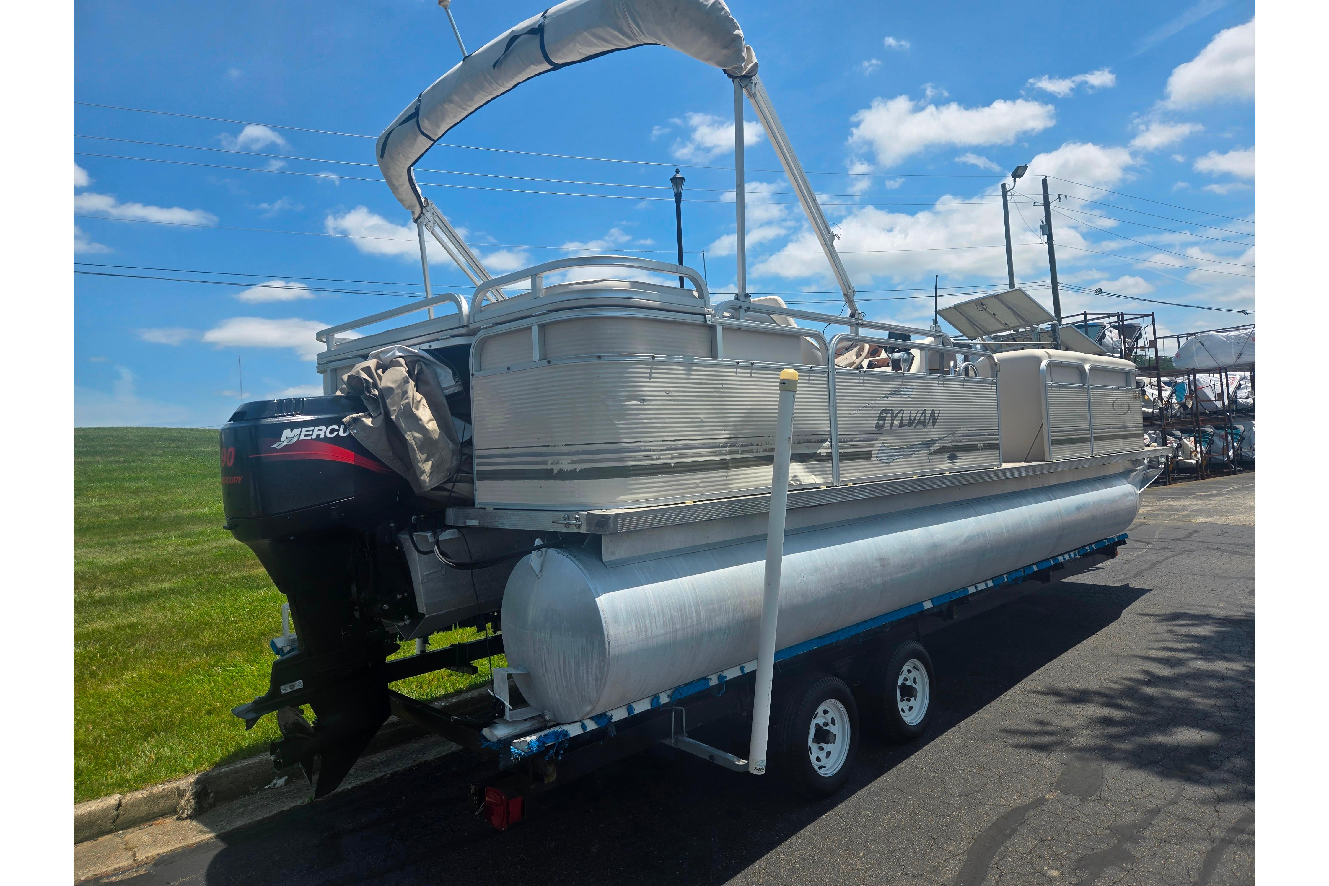 2000 Sylvan 824 Elite Cruise pontoon boat on trailer under blue sky.