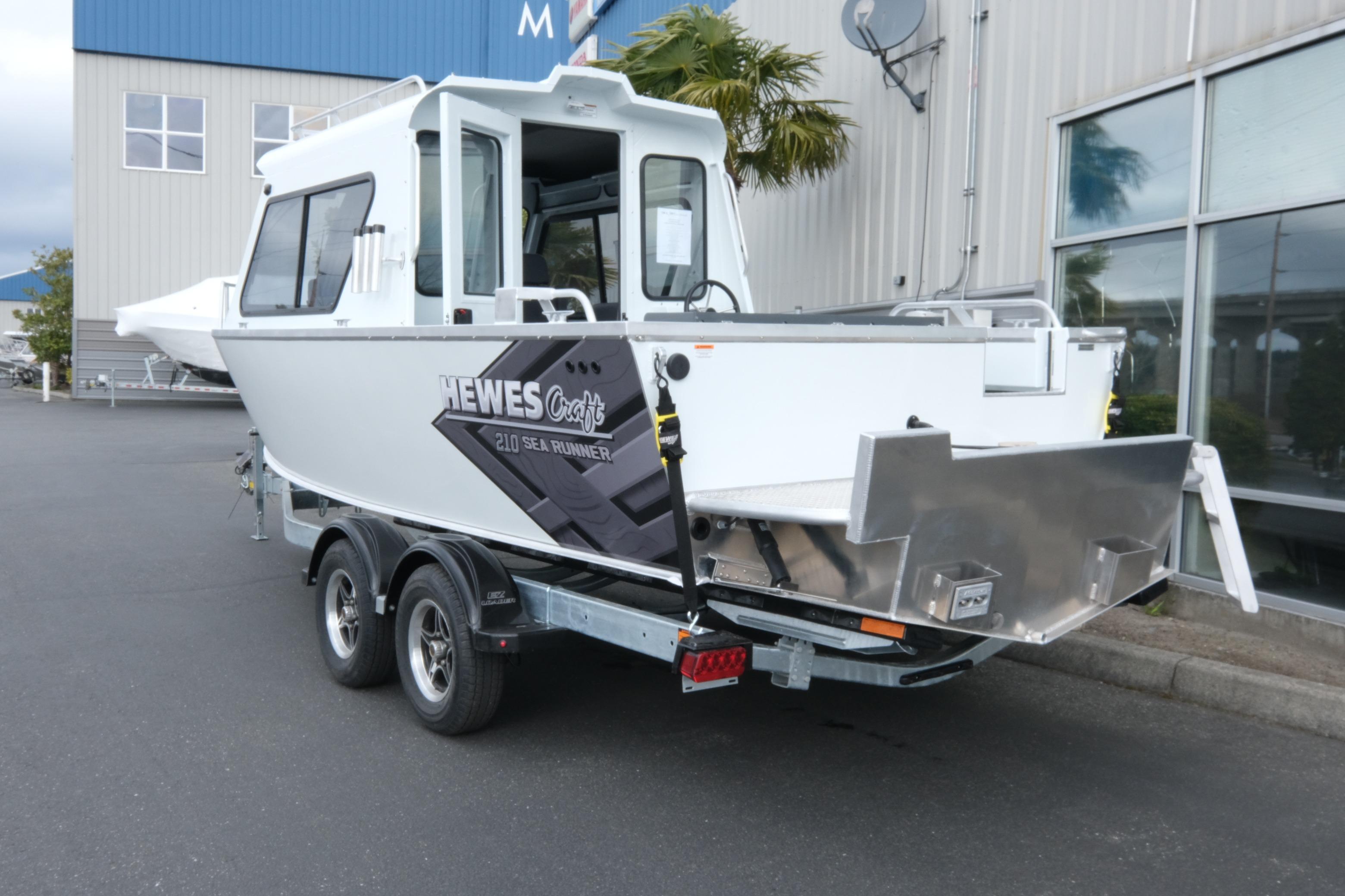 2026 Hewescraft 210 Sea Runner ET Hardtop boat on trailer, parked outside a building.