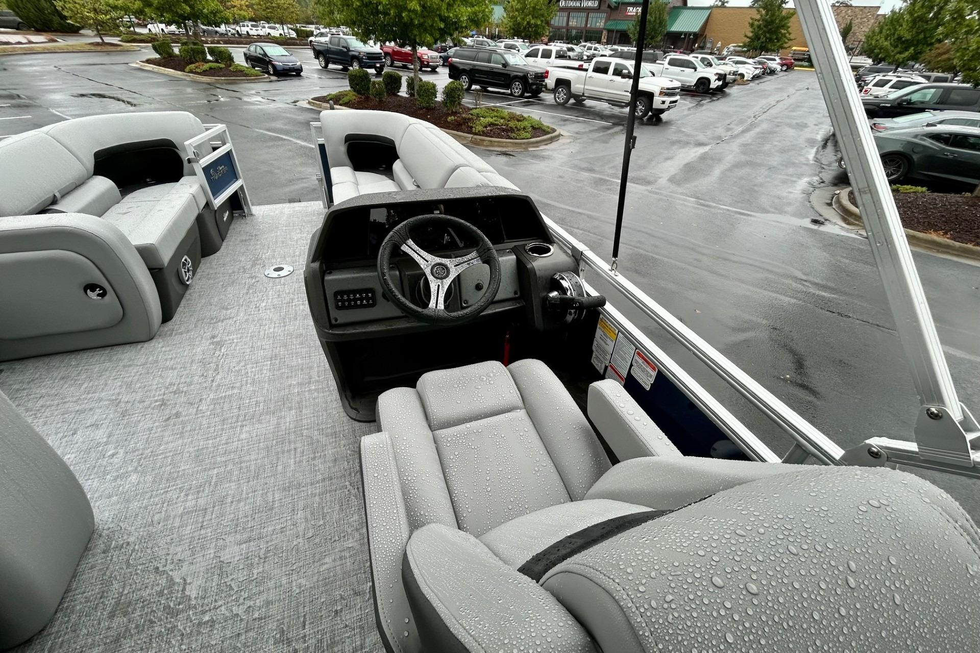 2026 Sun Tracker SportFish 22 DLX pontoon boat interior with wet seats in parking lot.