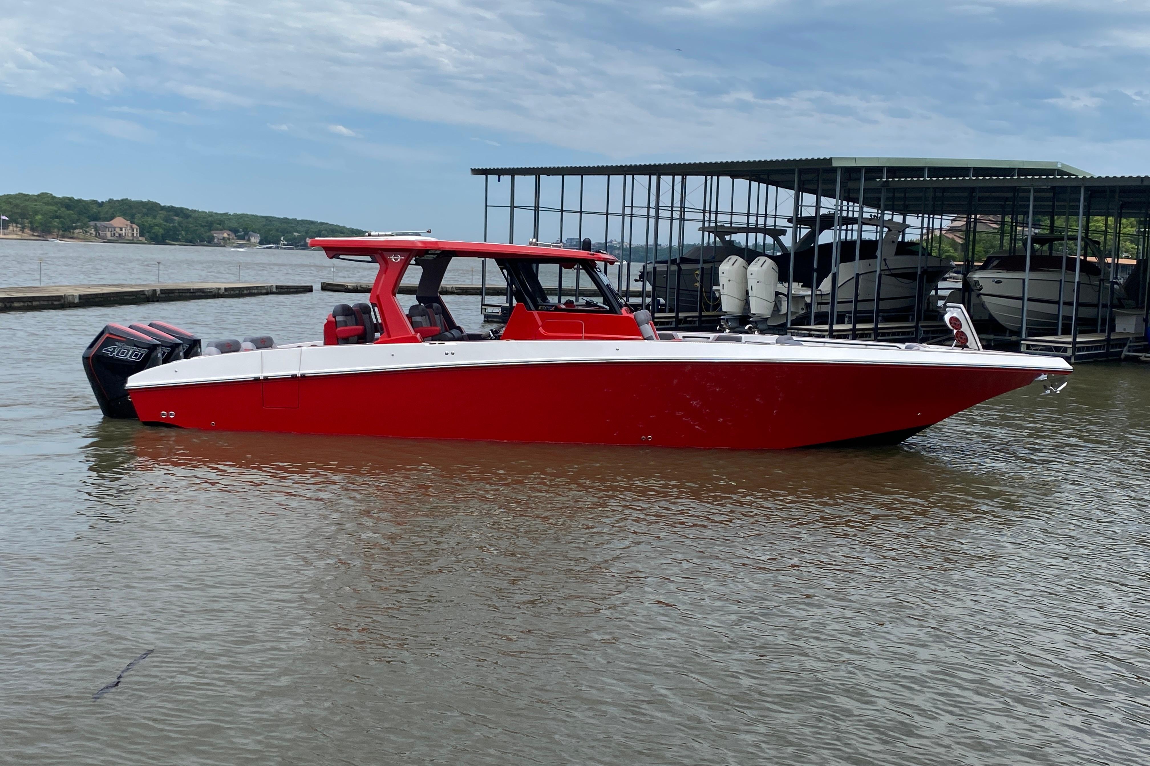 2025 Fountain 38 SCX boat in vibrant red, docked on a calm lake.