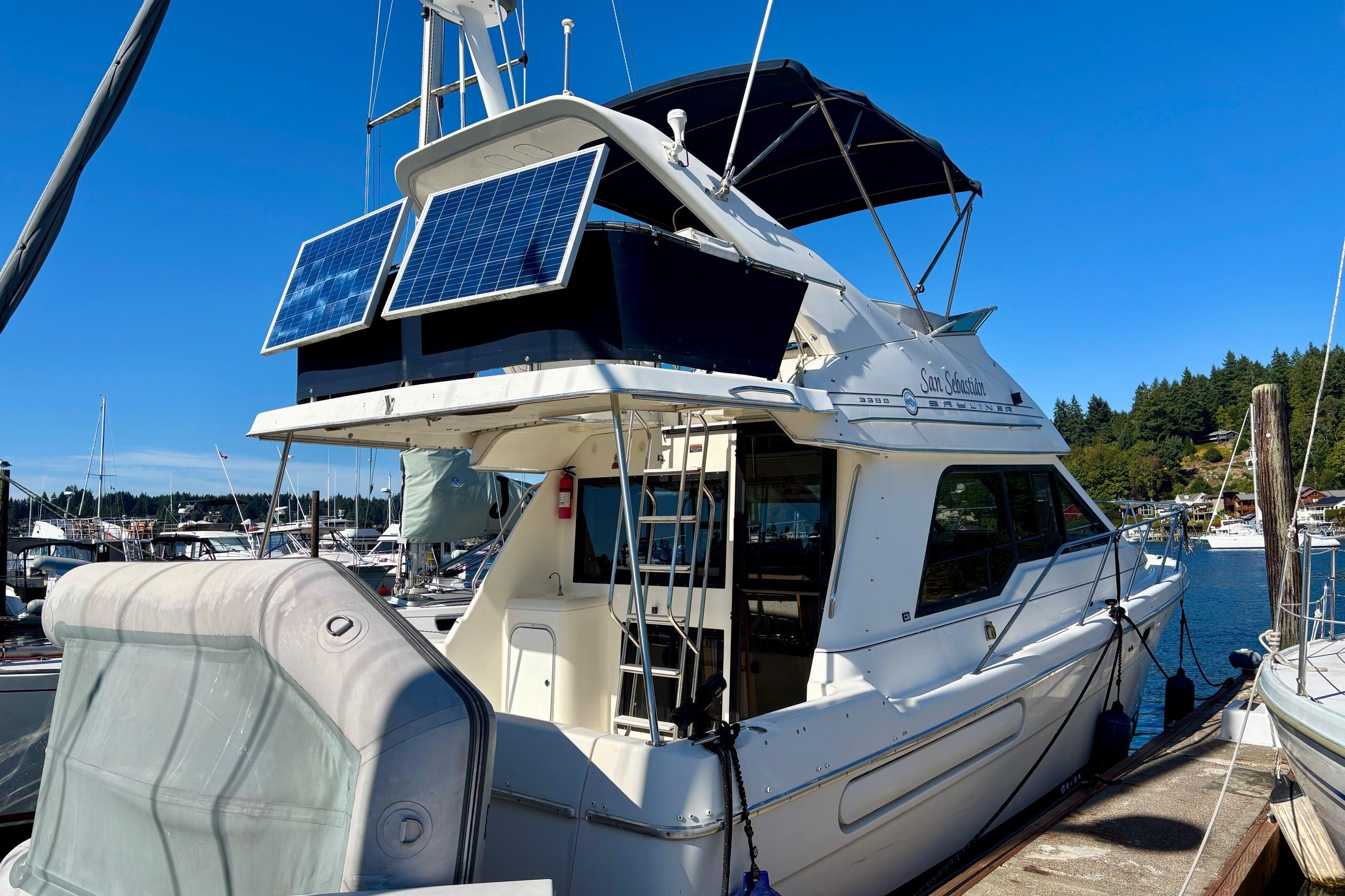 1998 Bayliner 3388 Command Bridge Motoryacht with solar panels docked at marina.