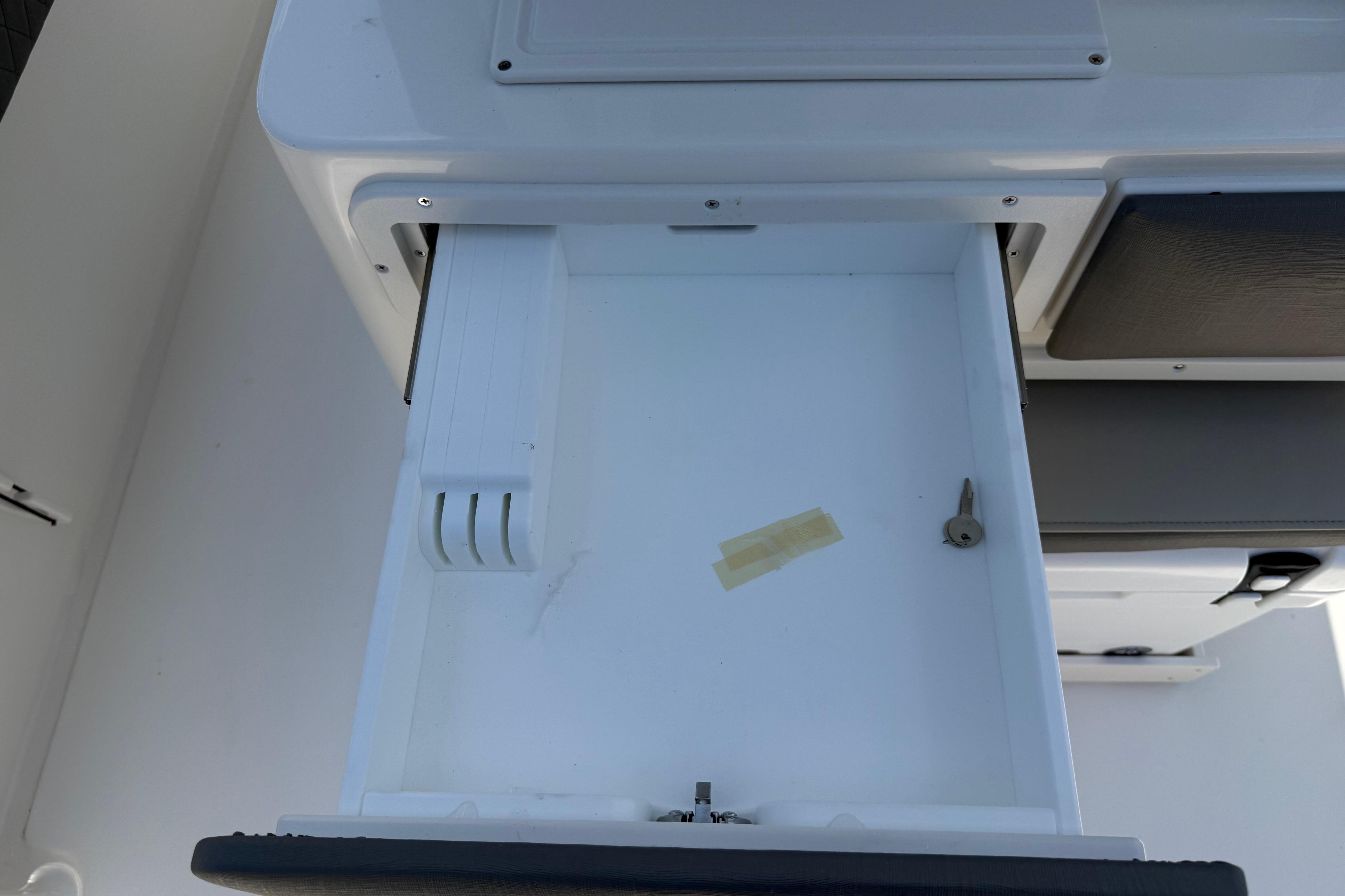 Open storage compartment on a 2027 Key West 249 FS boat, featuring a key and tape.