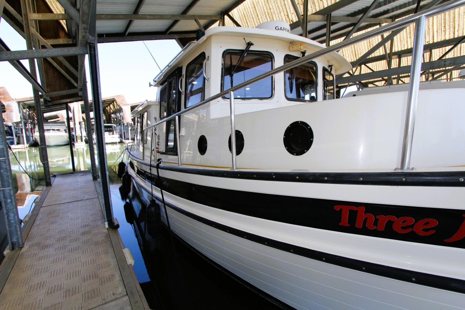 2002 Nordic Tug 37 docked in a covered marina, side view.