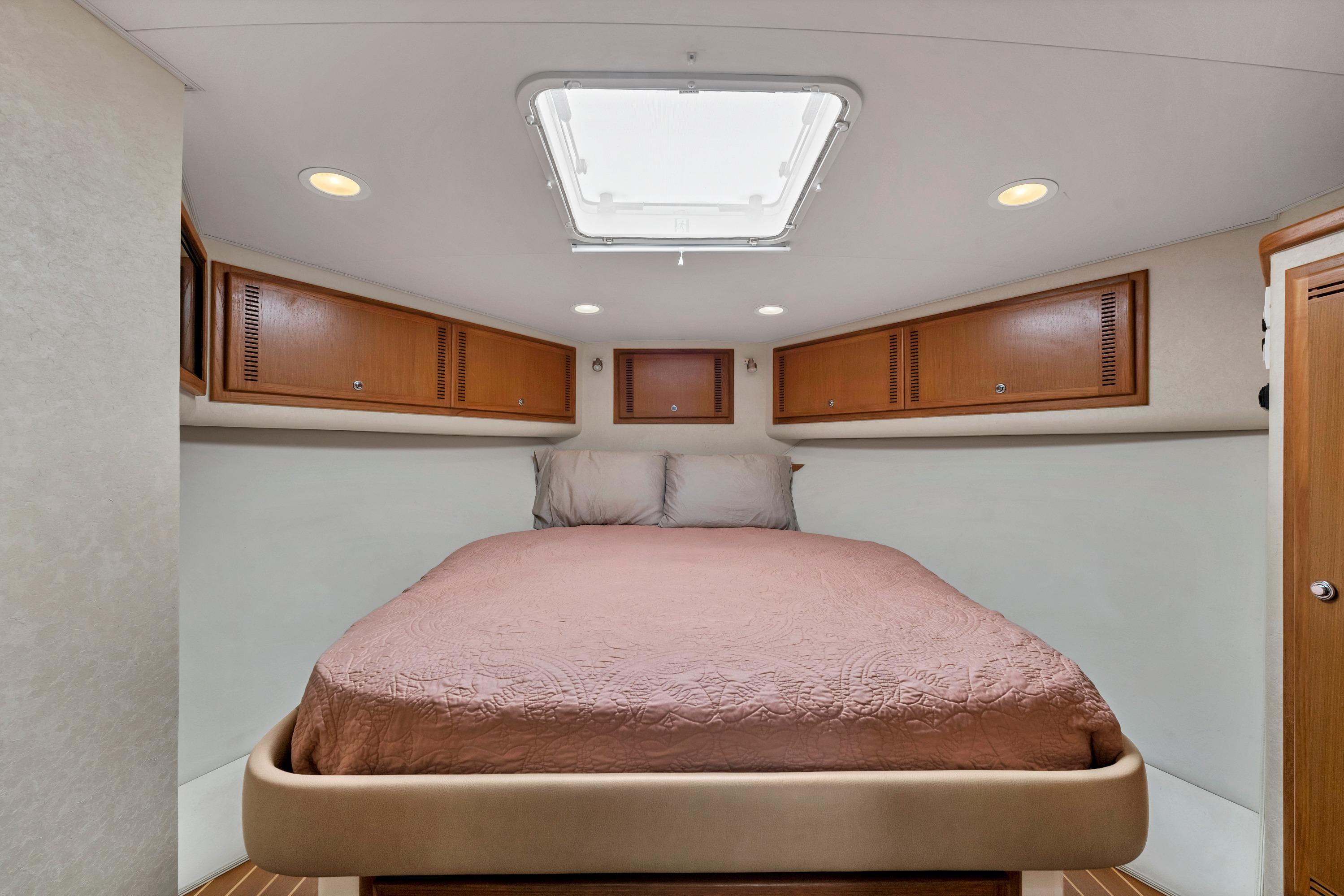 2010 Cabo 45 Express cabin interior with bed, wooden cabinets, and ceiling hatch.