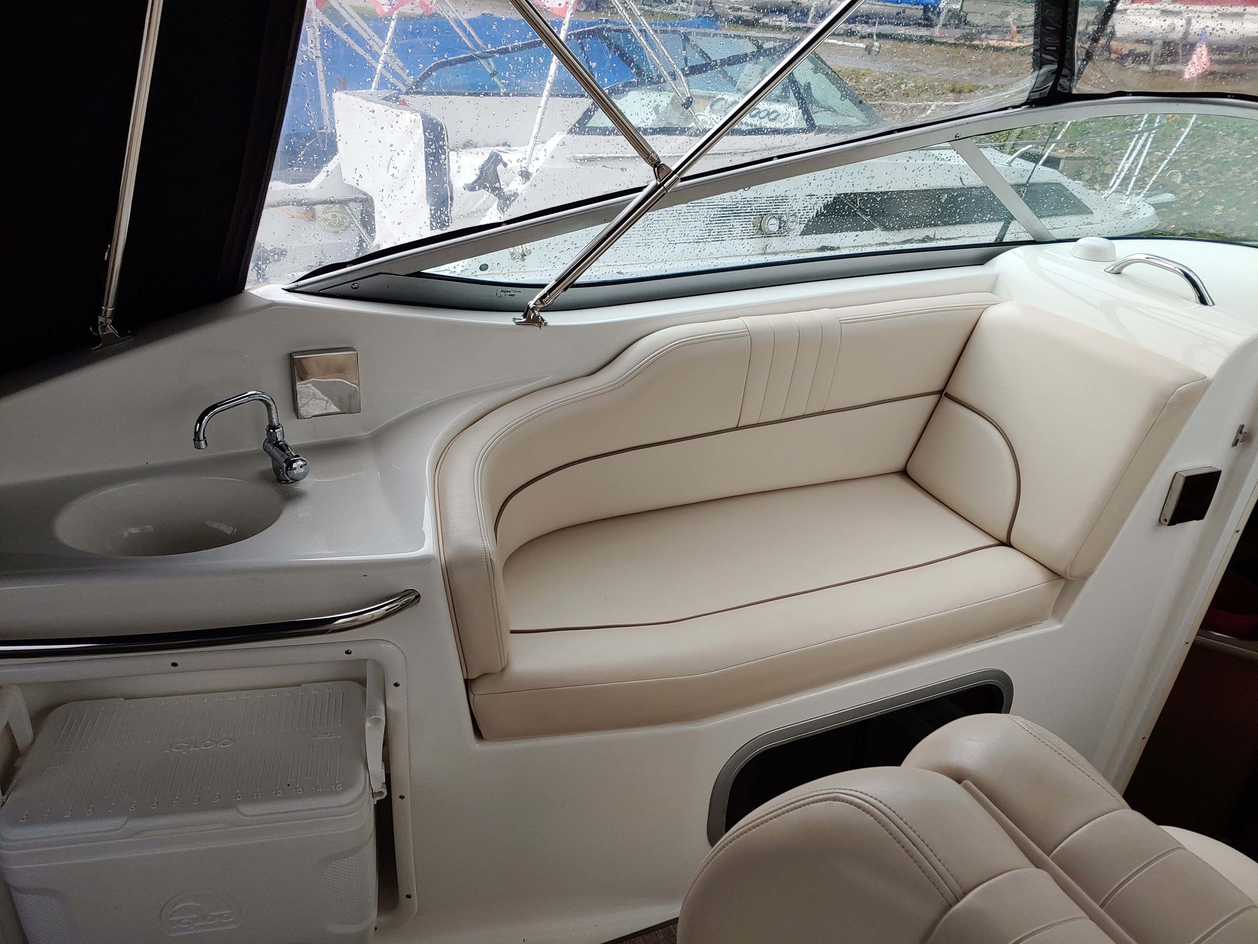 Interior of a boat with beige seating area and small sink.