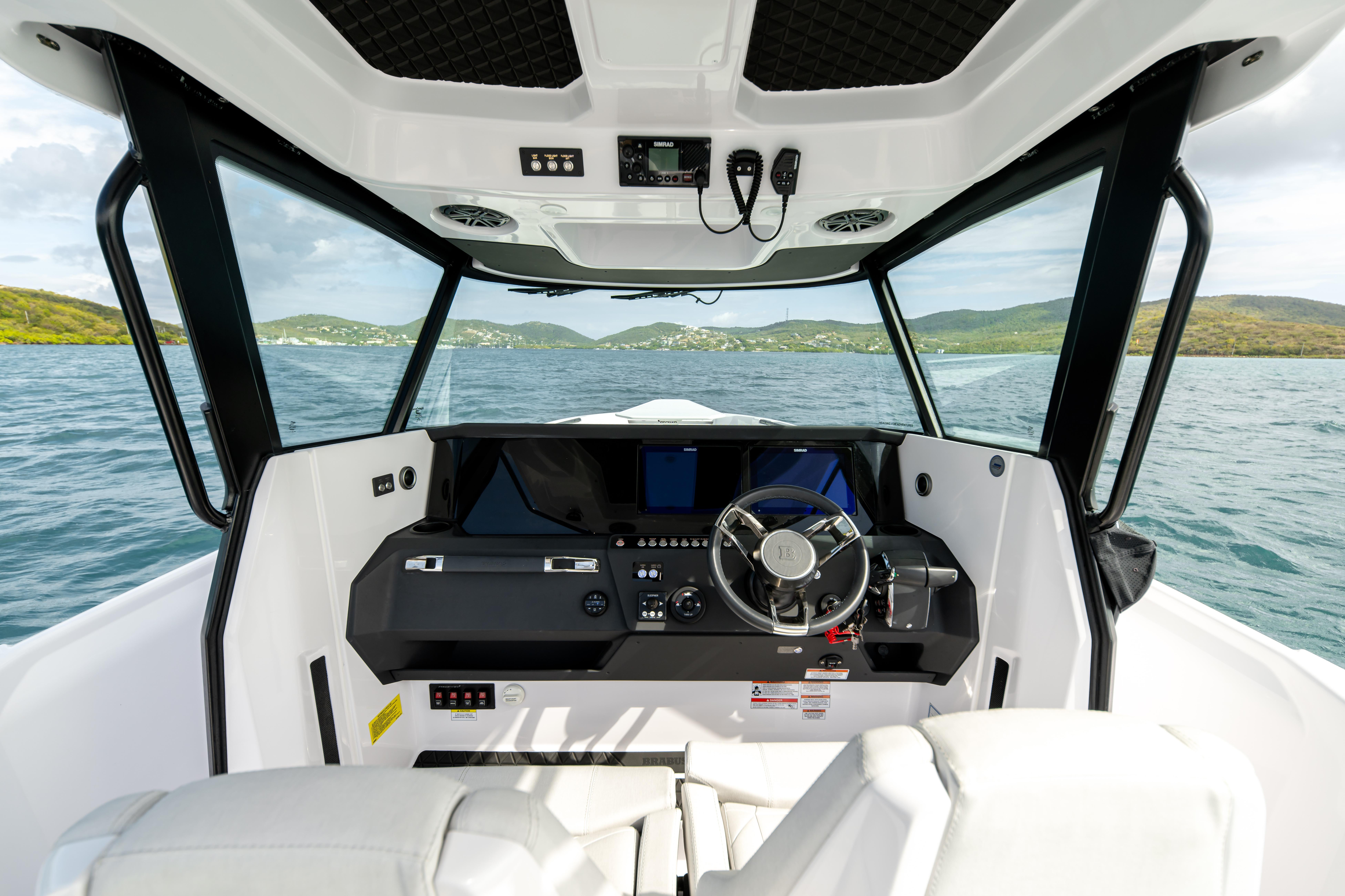 Interior view of 2025 Axopar 29 CCX boat cockpit with modern controls and scenic ocean backdrop.