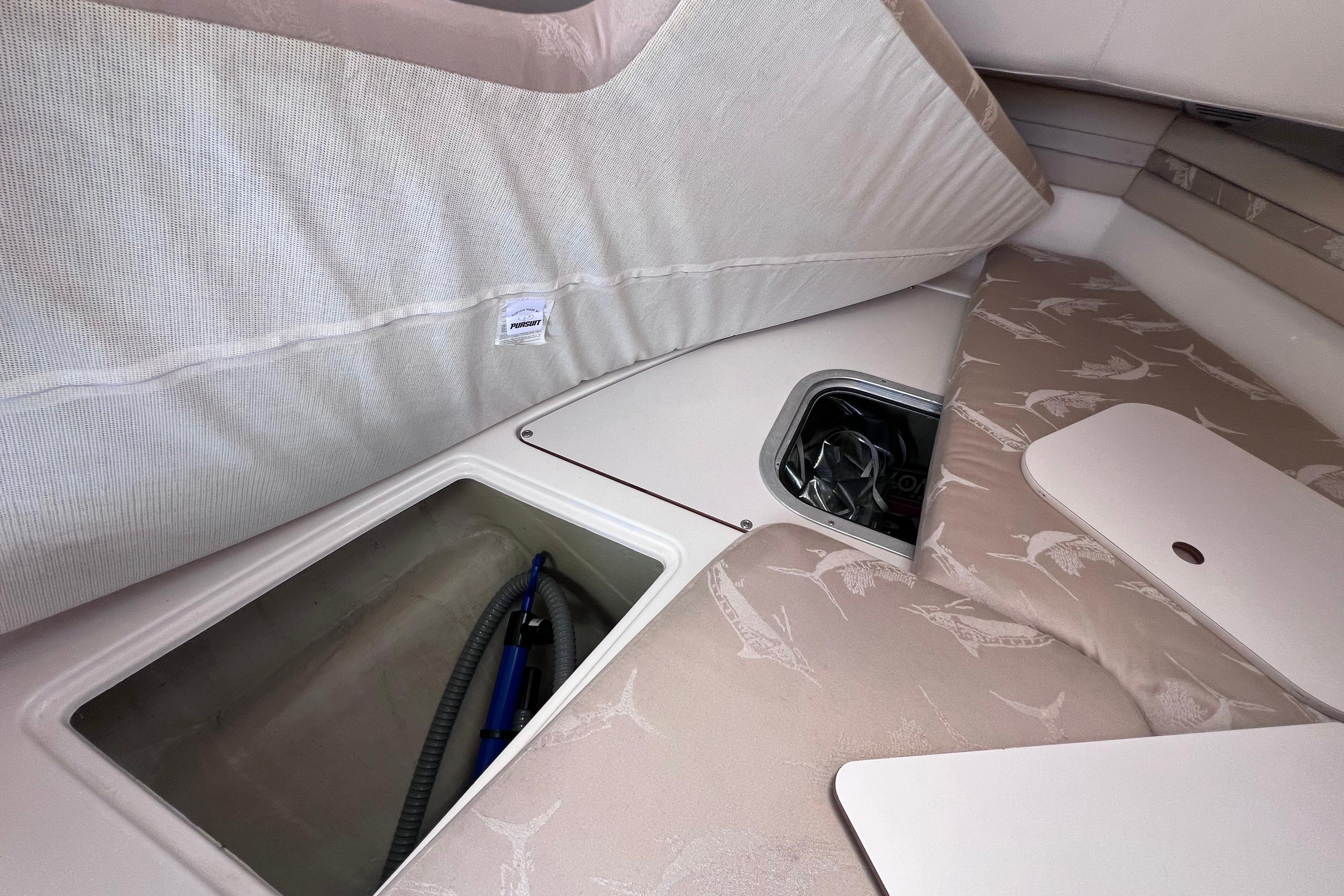 2004 Pursuit 2870 Walkaround cabin interior with storage compartments and patterned cushions.