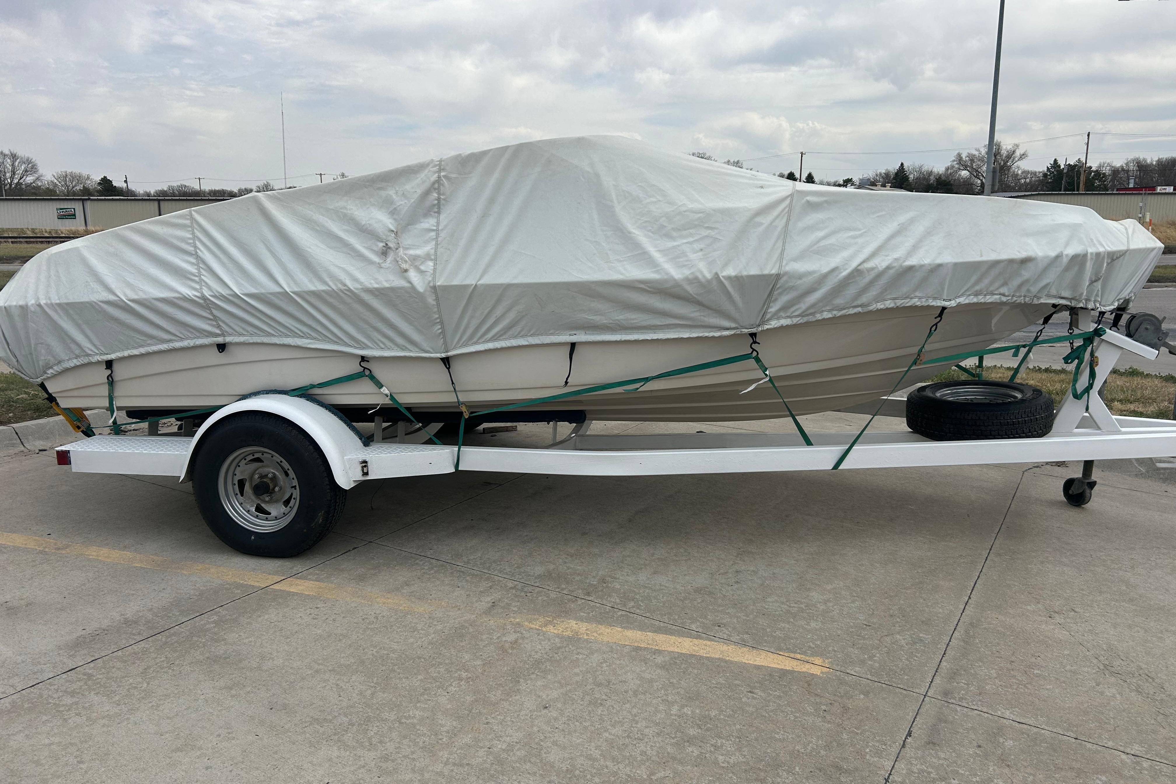 Covered 1996 Mariah 180 Shabah boat on trailer in parking lot.