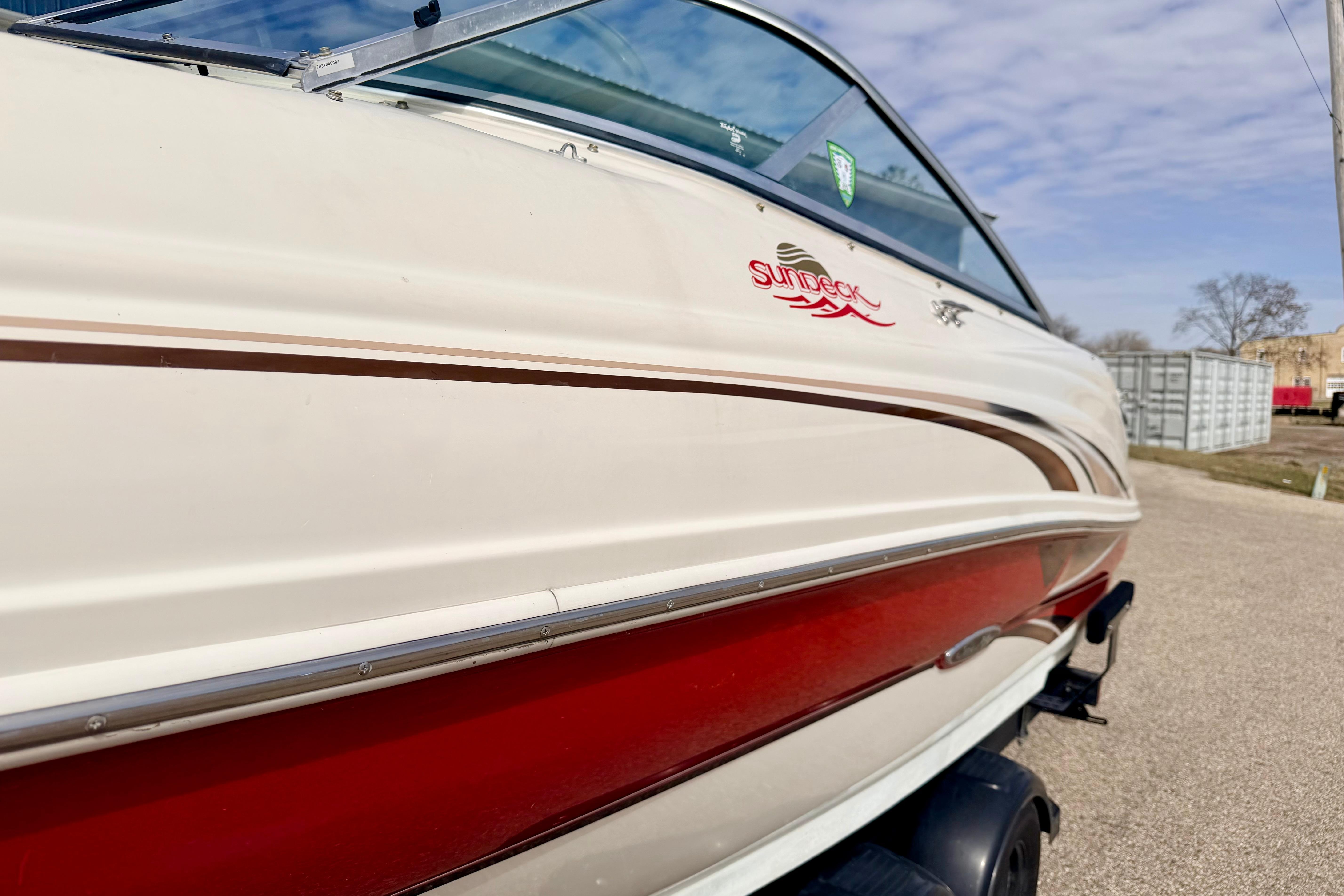 2003 Sea Ray 200 Sundeck boat with red and white exterior, parked outdoors.
