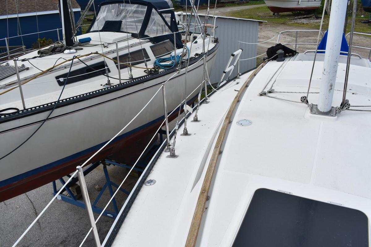 Two sailboats are side by side on a dry dock. One has a blue canopy.