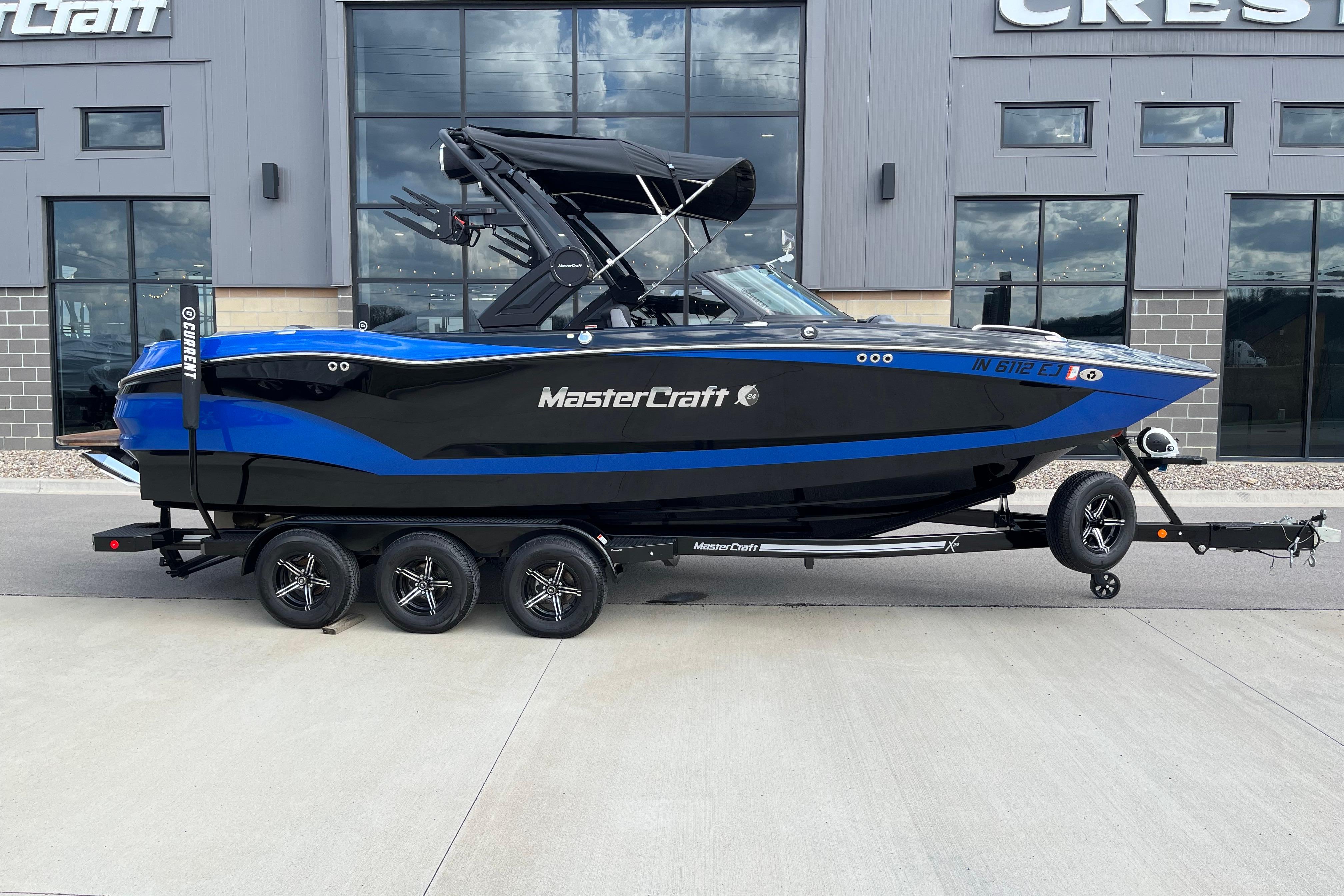 2022 MasterCraft X24 boat in blue and black on a trailer outside a dealership.