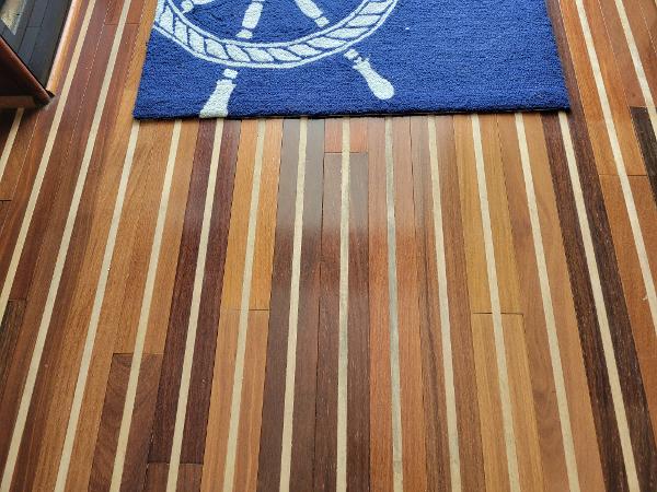 Wooden floor with a blue rug featuring a ship's wheel design.