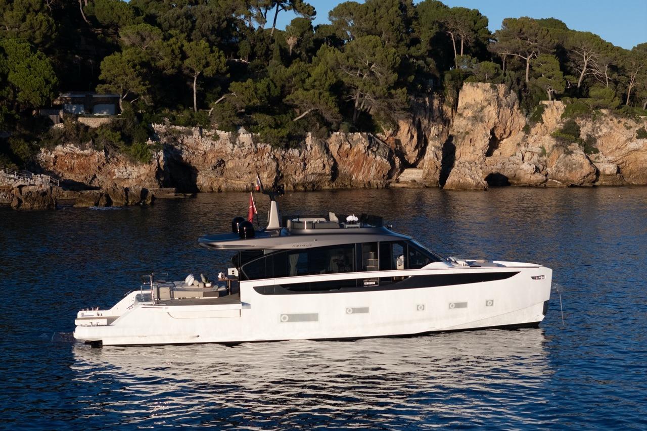 2025 Azimut Seadeck 7 yacht cruising near rocky coastline with lush greenery.