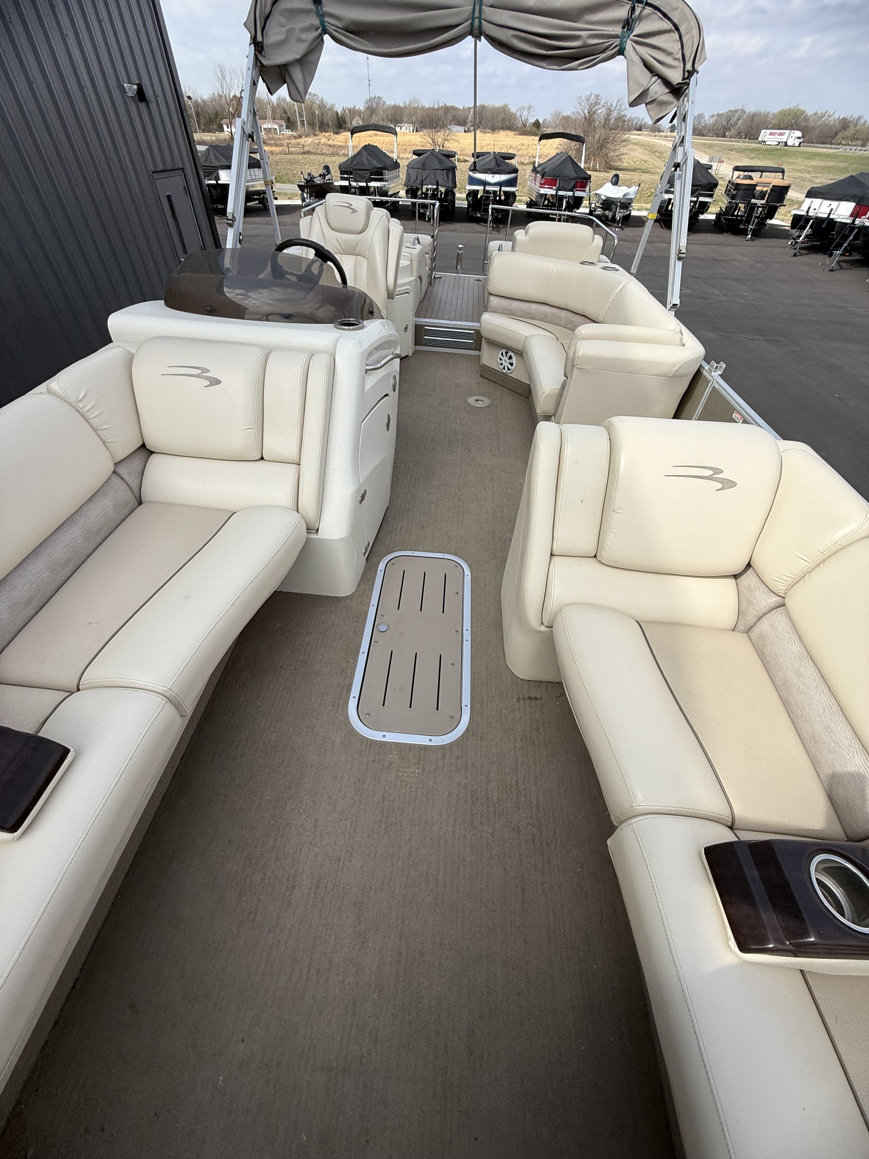 Interior view of a 2014 Bennington 2575RCW-I/O pontoon boat with beige seating.