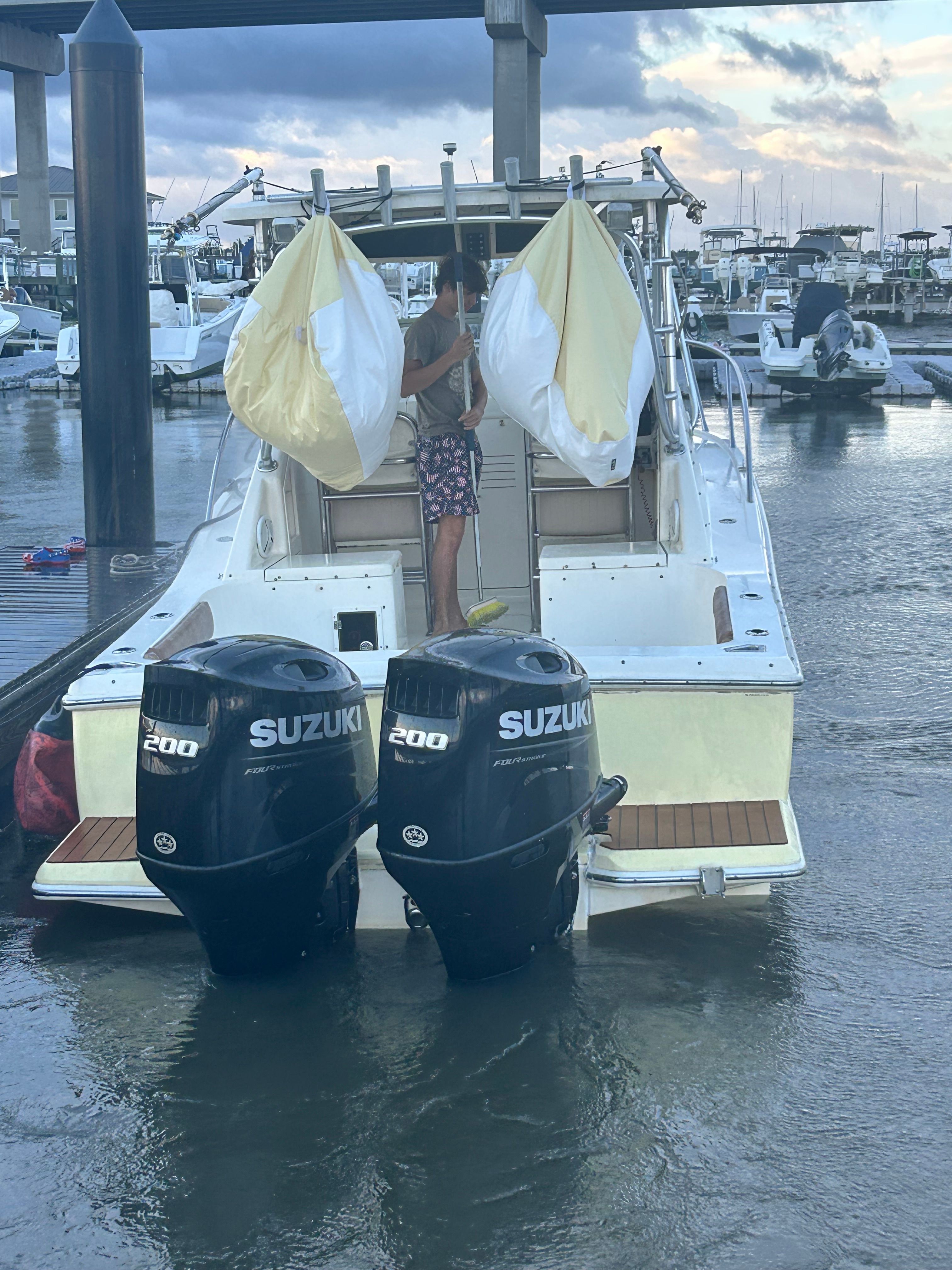 A 2003 Scout 280 Abaco docked with two Suzuki engines and a person on board.