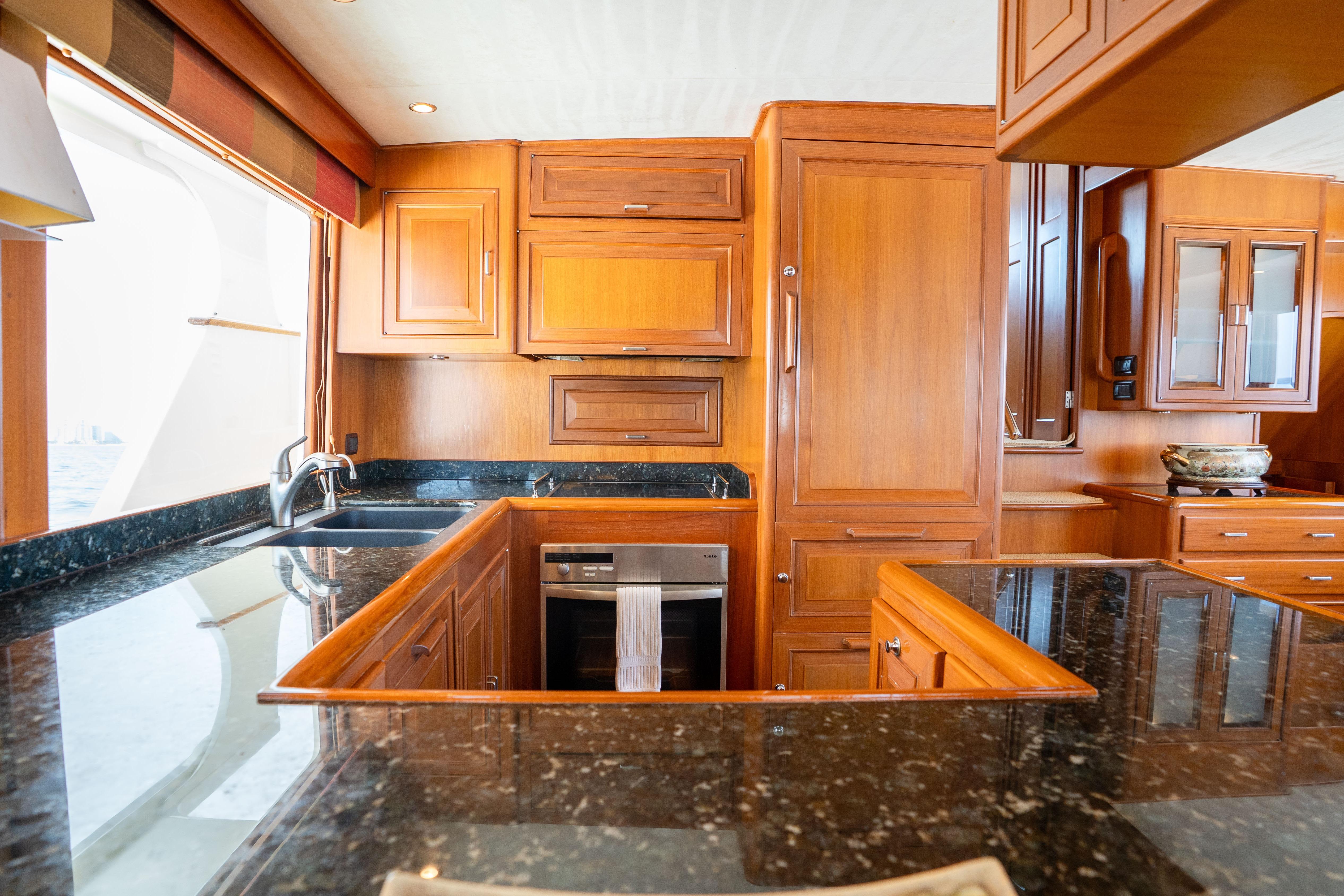 Luxurious wooden kitchen interior on a 2006 Fleming 75 yacht with granite countertops.