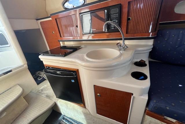 2003 Sea Ray 260 Sundancer cabin with kitchenette, featuring sink, microwave, and mini fridge.