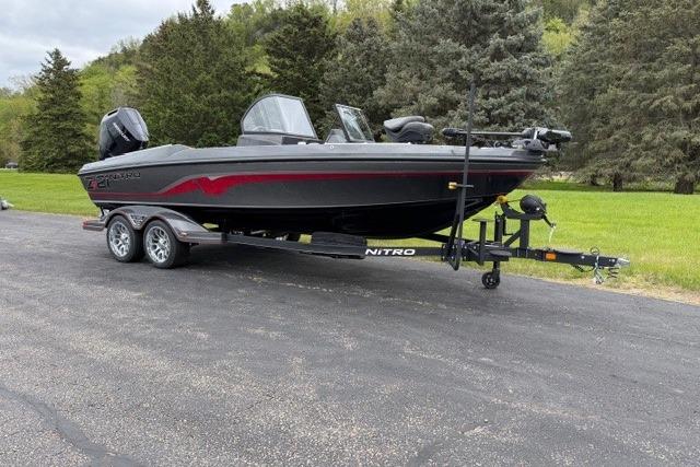 2024 Nitro ZV21 boat on trailer, parked on paved road with lush greenery background.