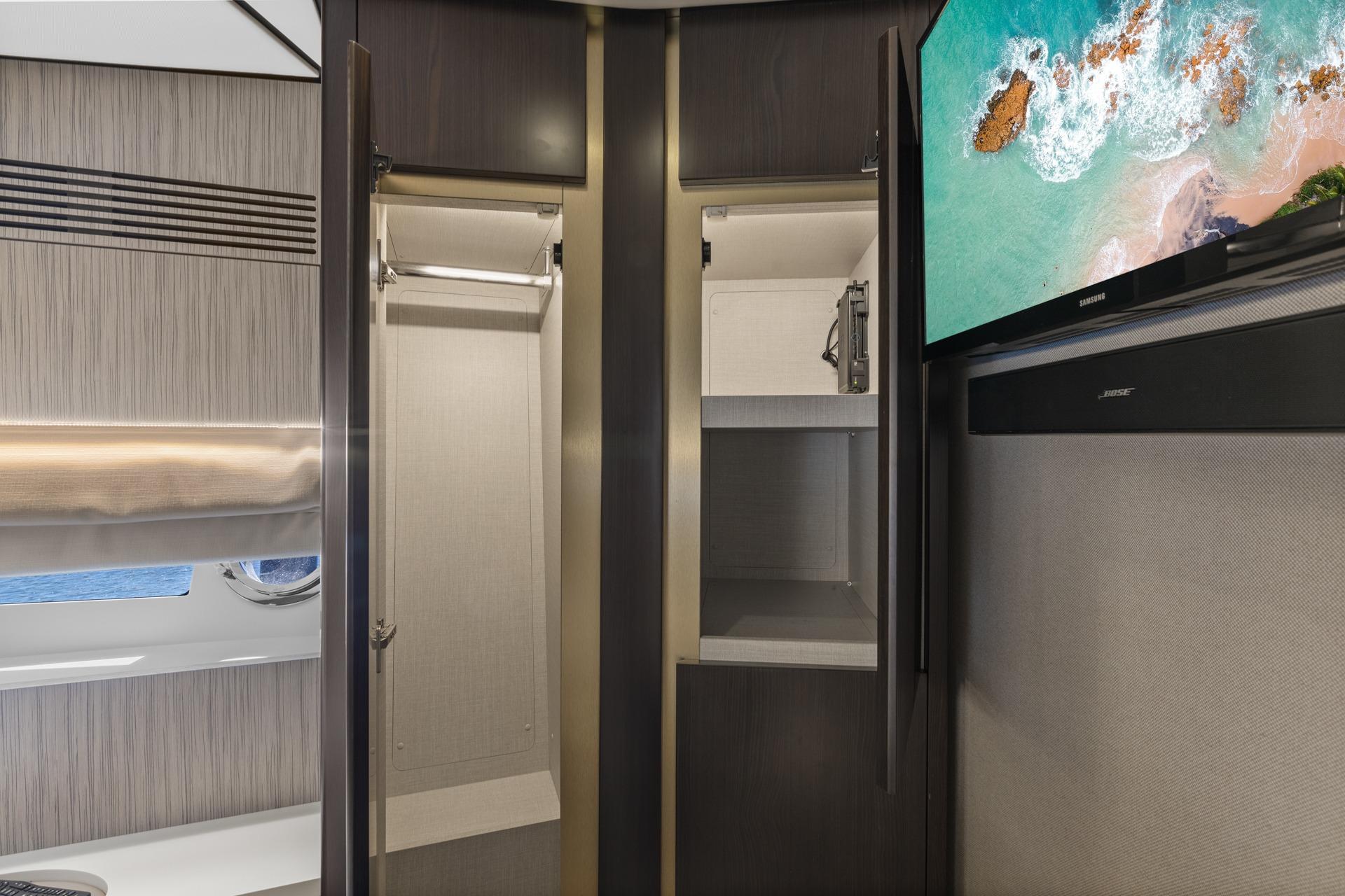 Interior of 2019 Azimut 55 yacht with open closet and mounted TV.