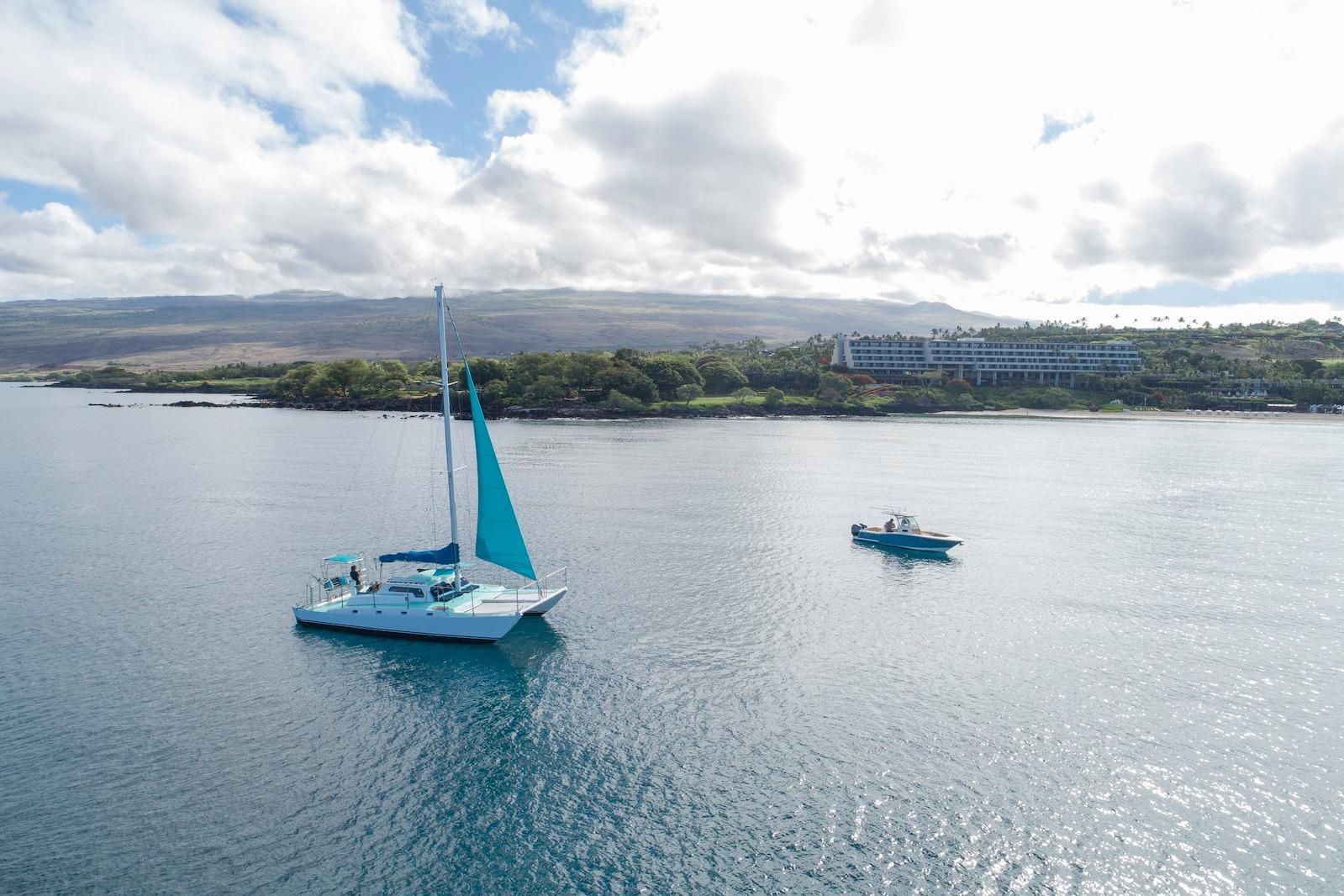 1978 CSK Beach Catamaran sailing near a scenic coastline under a cloudy sky.