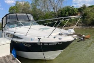 2012 Bayliner 285 Cruiser docked on a calm lake with trees in the background.