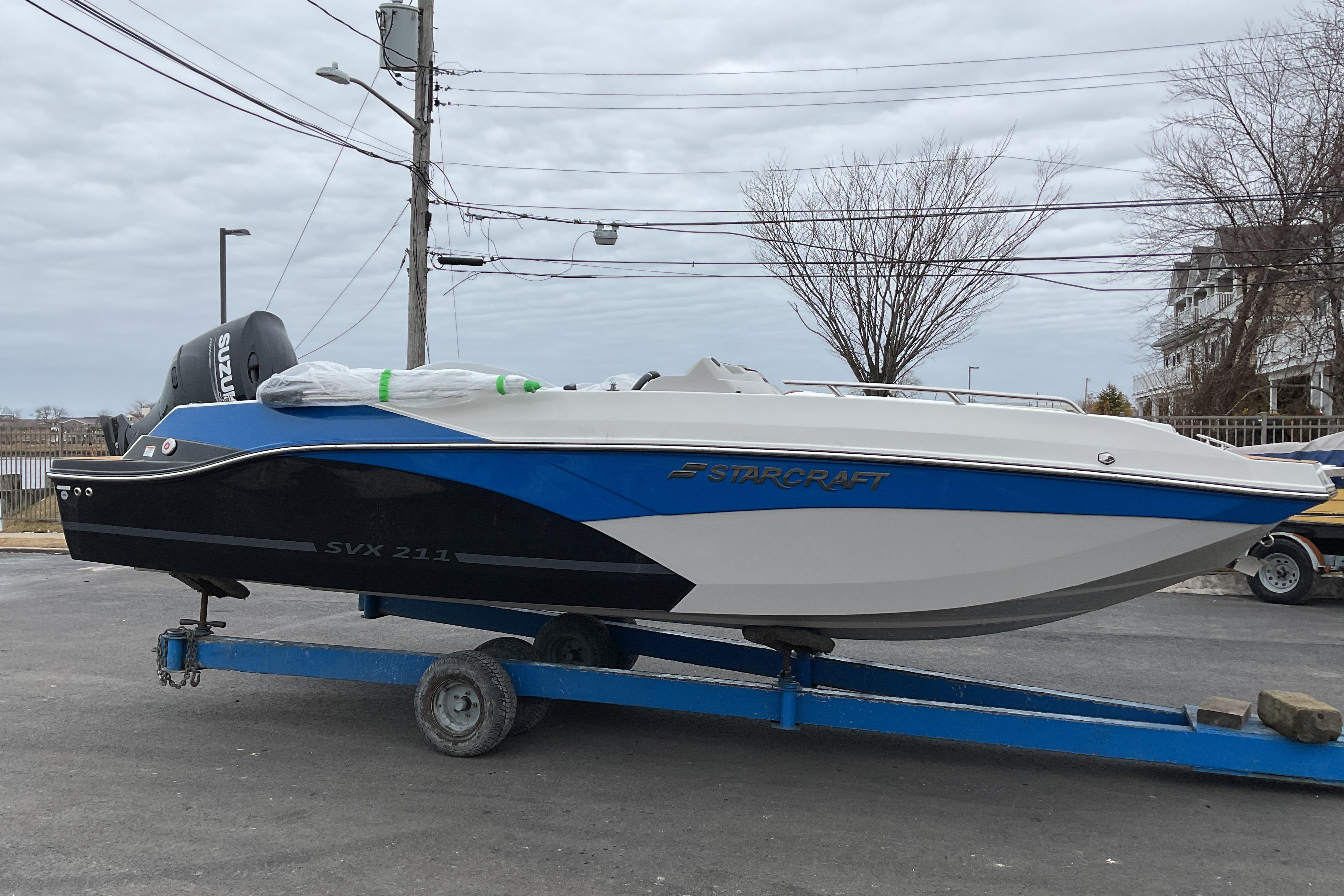 2026 Starcraft SVX 211 OB boat on trailer, blue and white design, parked outdoors.