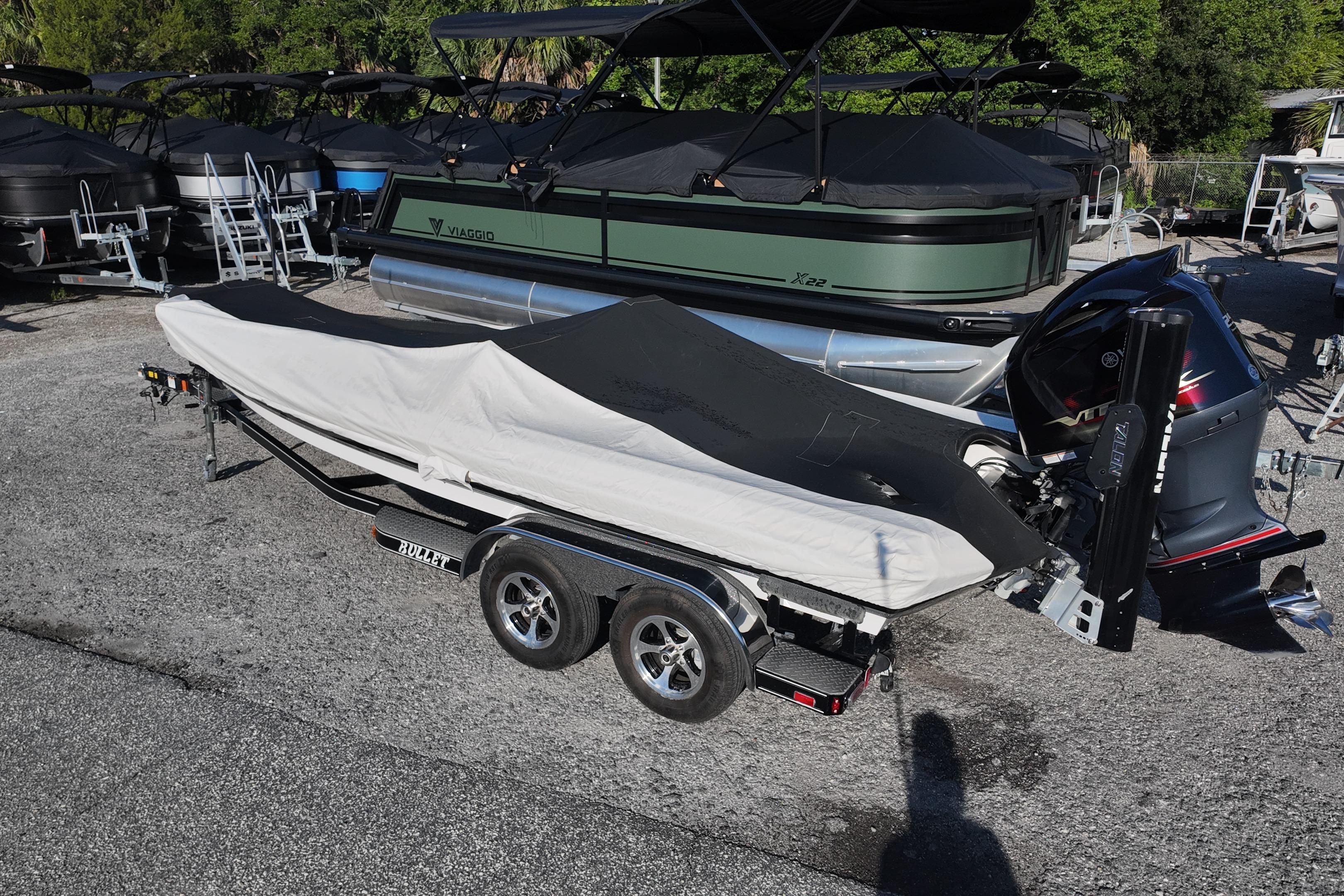 Covered 2022 Bullet 21SDC boat on trailer, parked near other boats in a lot.