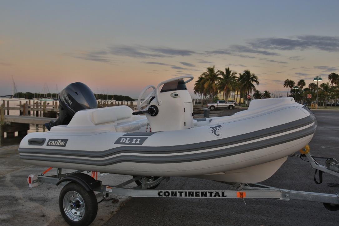 2025 Caribe DL11 inflatable boat on trailer at sunset by the water.
