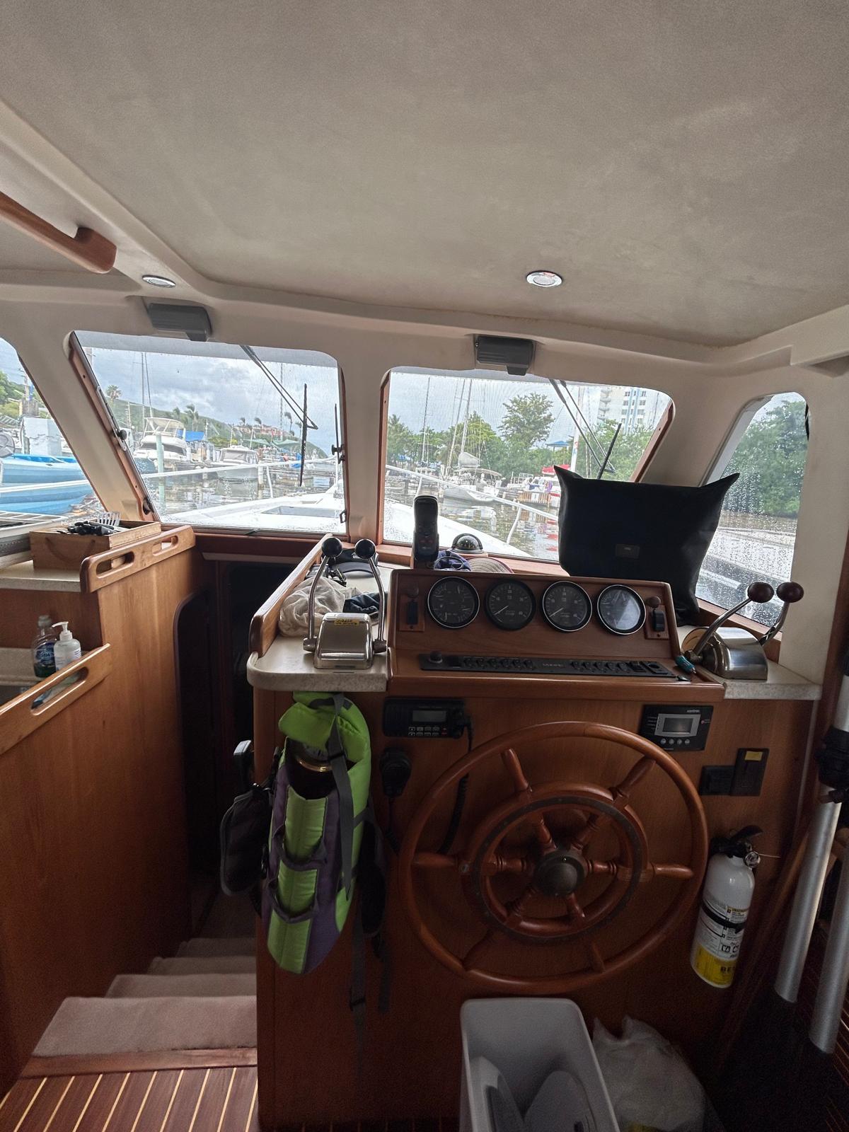 1999 Mainship 350 Trawler helm with wooden wheel and navigation instruments.