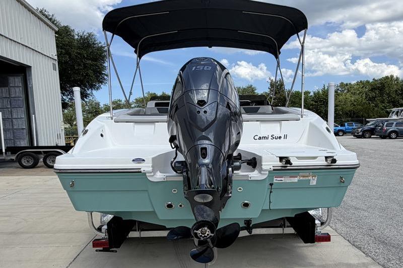 2026 Hurricane SunDeck Sport 2050 OB boat with outboard motor, parked outdoors.