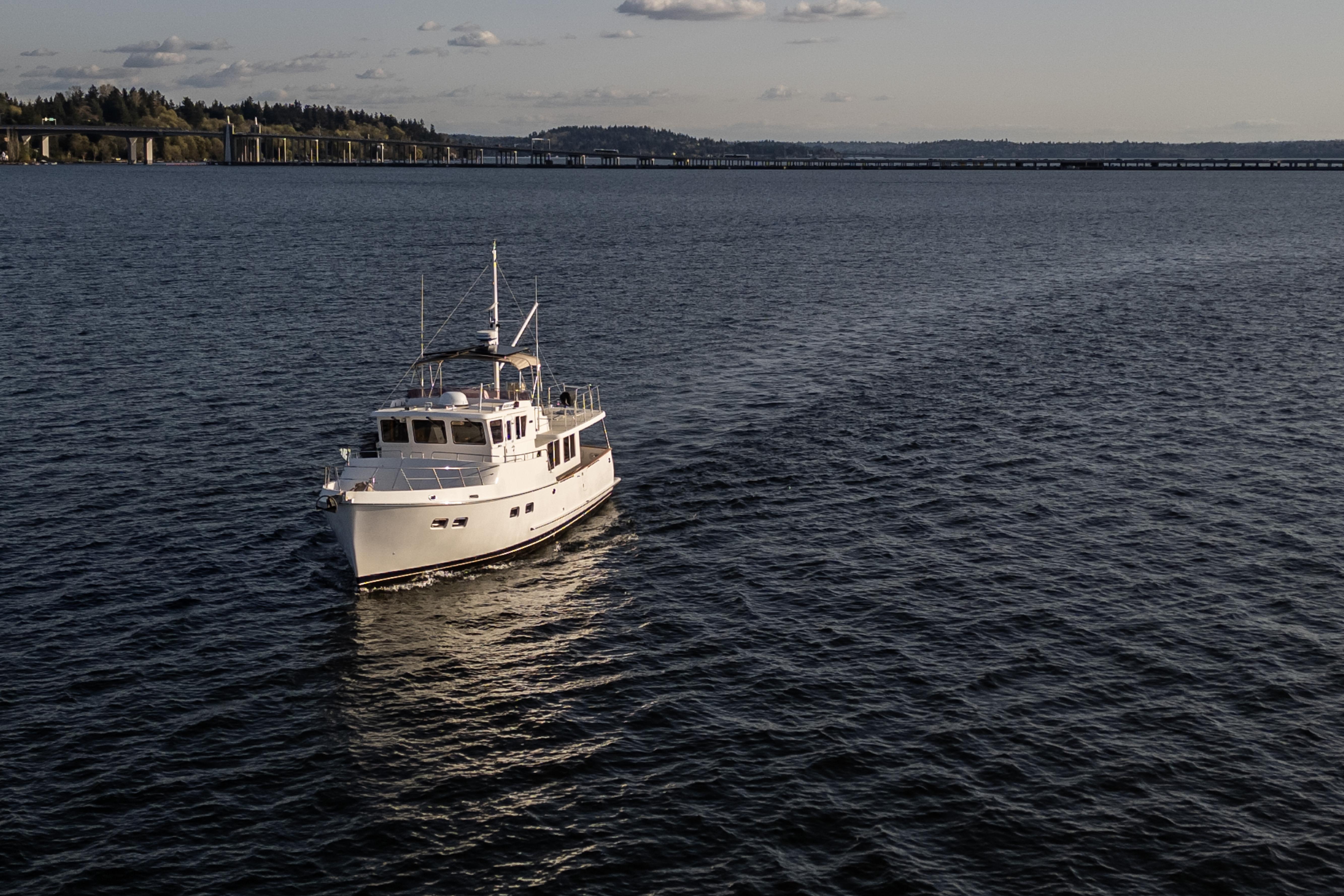 Selene 47 yacht from 2003 cruising on a calm lake with distant bridge view.