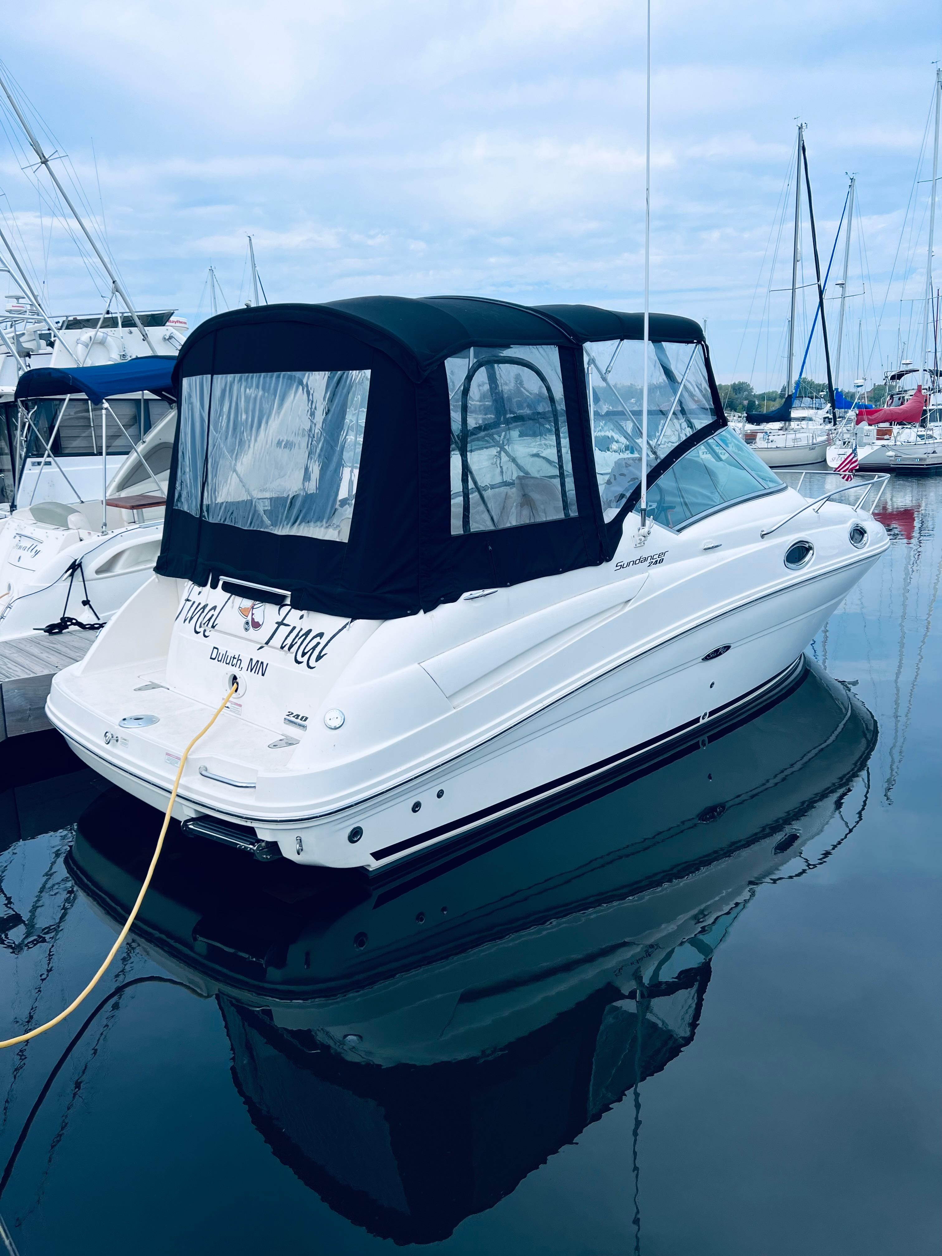 2012 Sea Ray 240 Sundancer boat docked in marina, featuring black canopy.