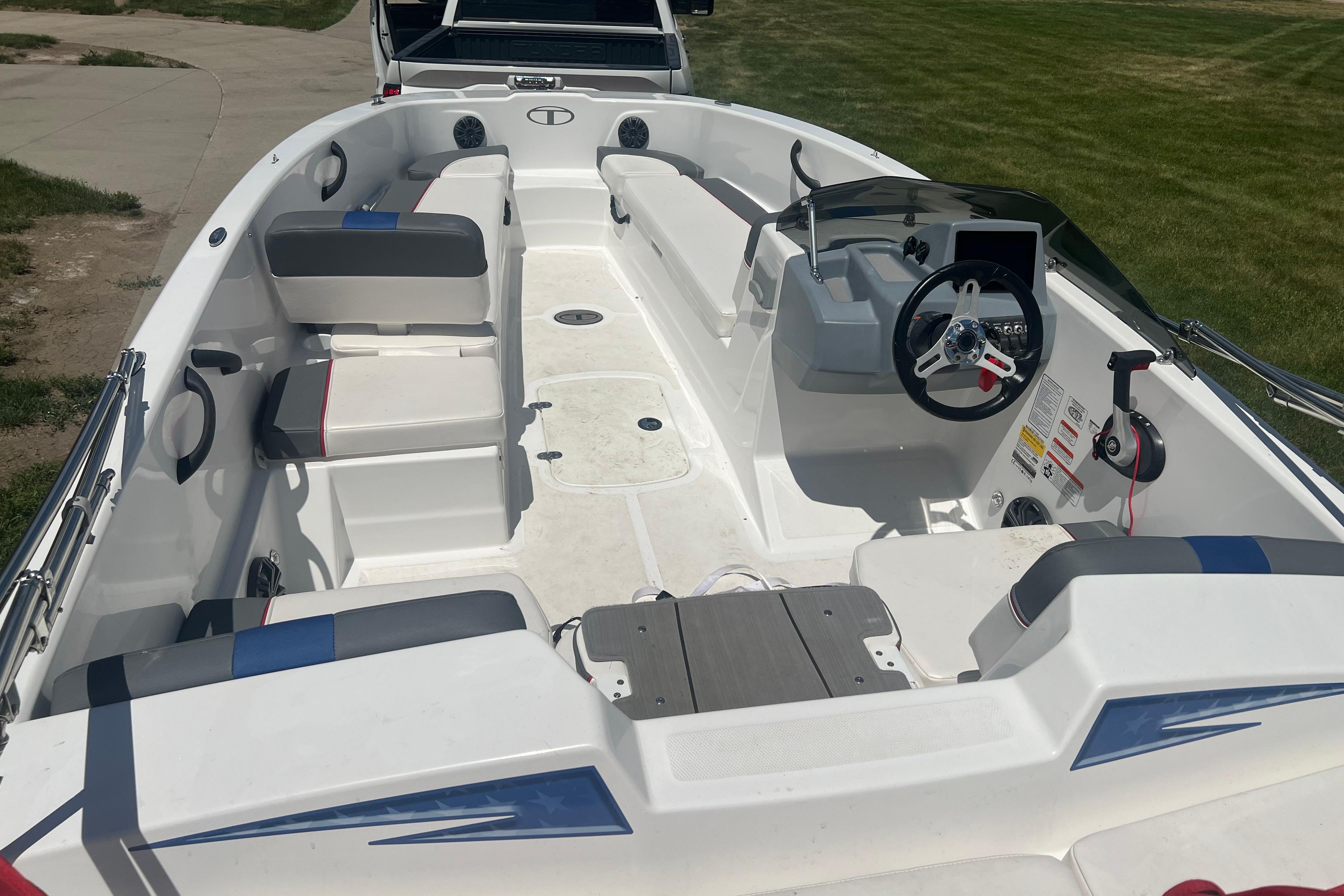 2023 Tahoe T18 boat interior with seating and steering wheel, parked on grass.