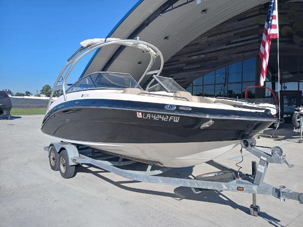 2010 Yamaha Boats 242 Limited on trailer, parked outdoors near a building with an American flag.