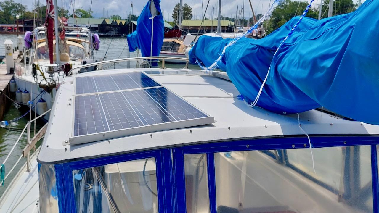 1981 Morgan Out Island 41 sailboat with solar panels and blue sails docked at marina.